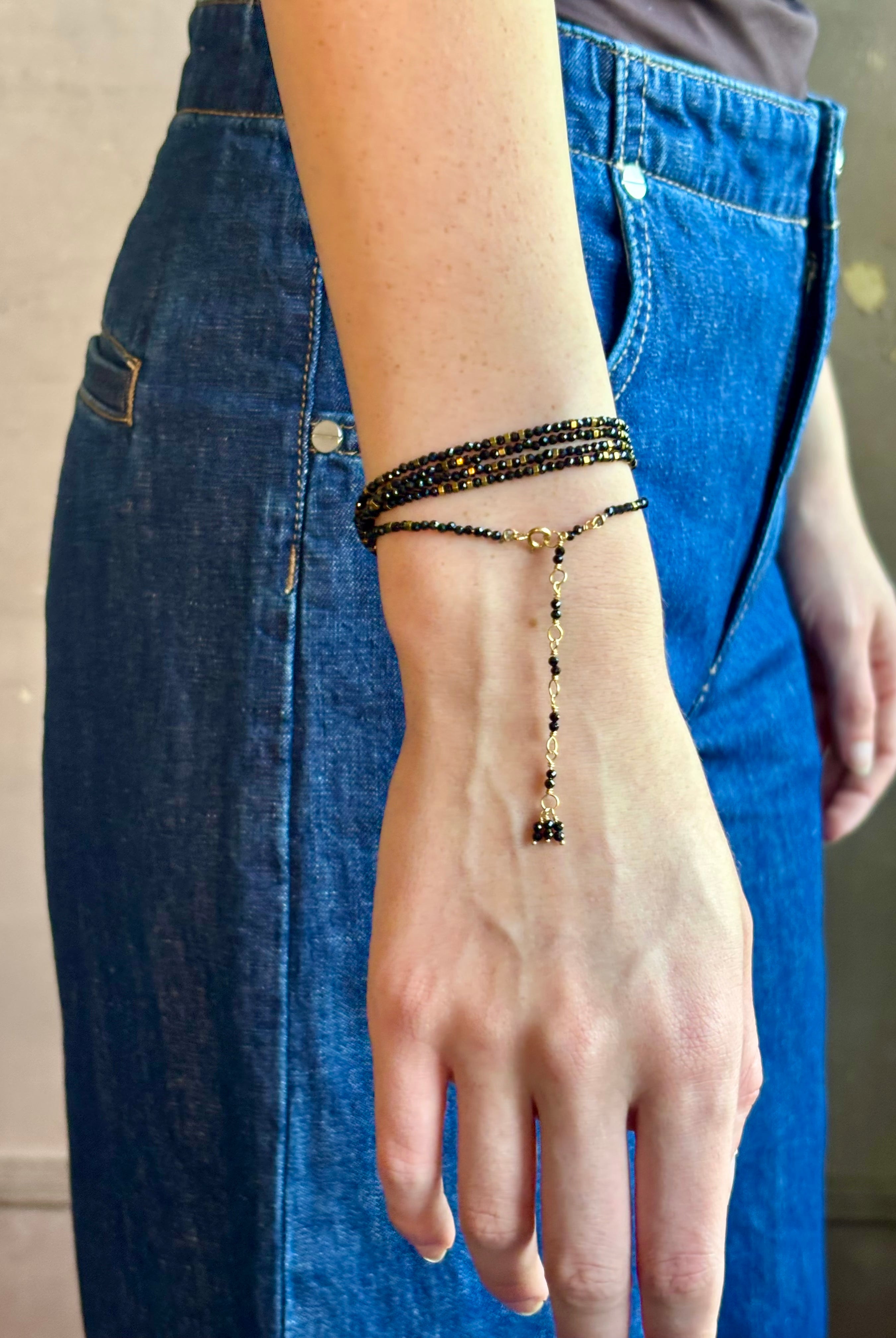 Woman wearing spinel confetti wrap Bracelet from Canadian fine jewelry artist Anne Sportun with natural stone spinel and 18k yellow gold beads that can double as a necklace perfect for travel