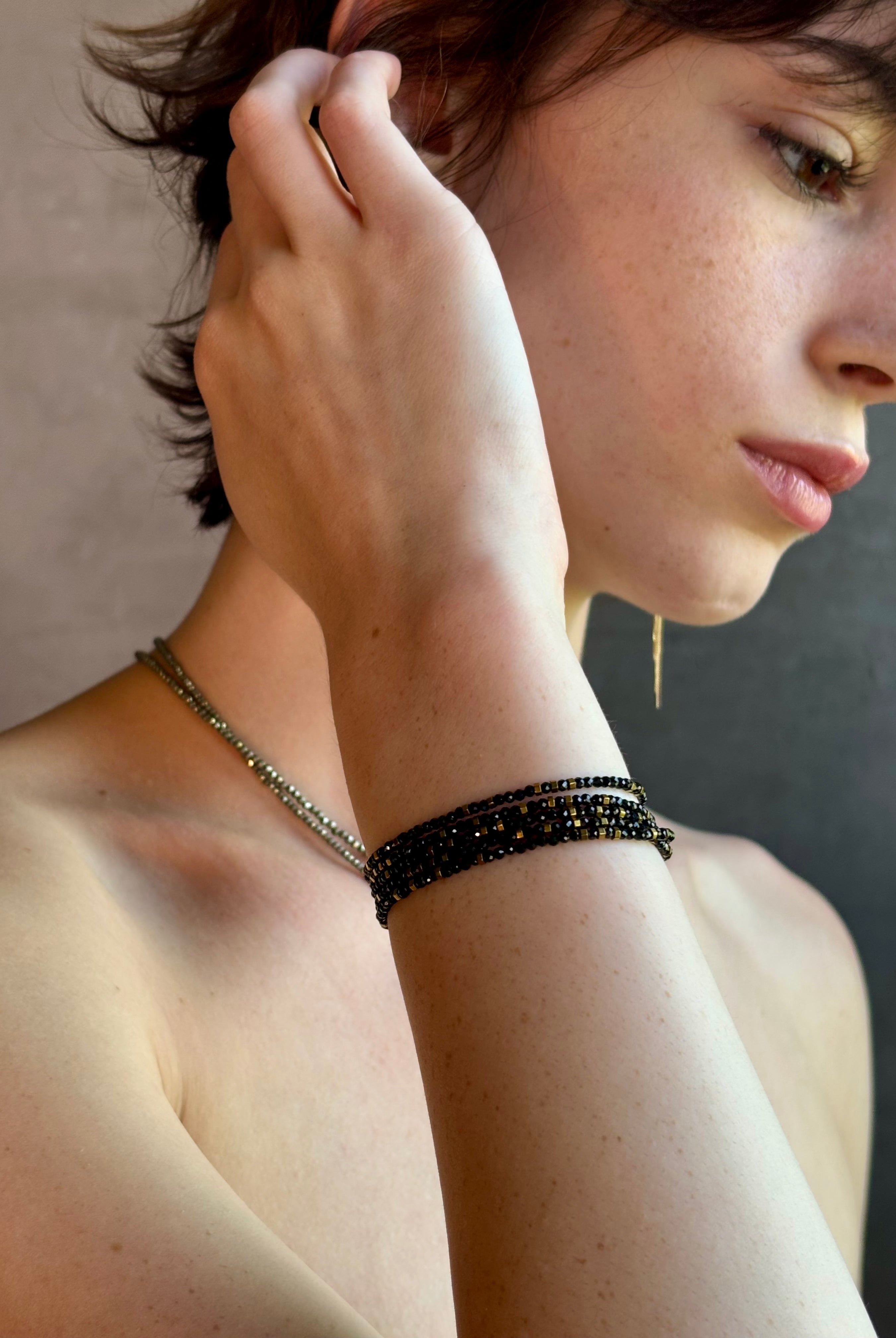 Woman wearing spinel confetti wrap Bracelet from Canadian fine jewelry artist Anne Sportun with natural stone spinel and 18k yellow gold beads that can double as a necklace perfect for travel