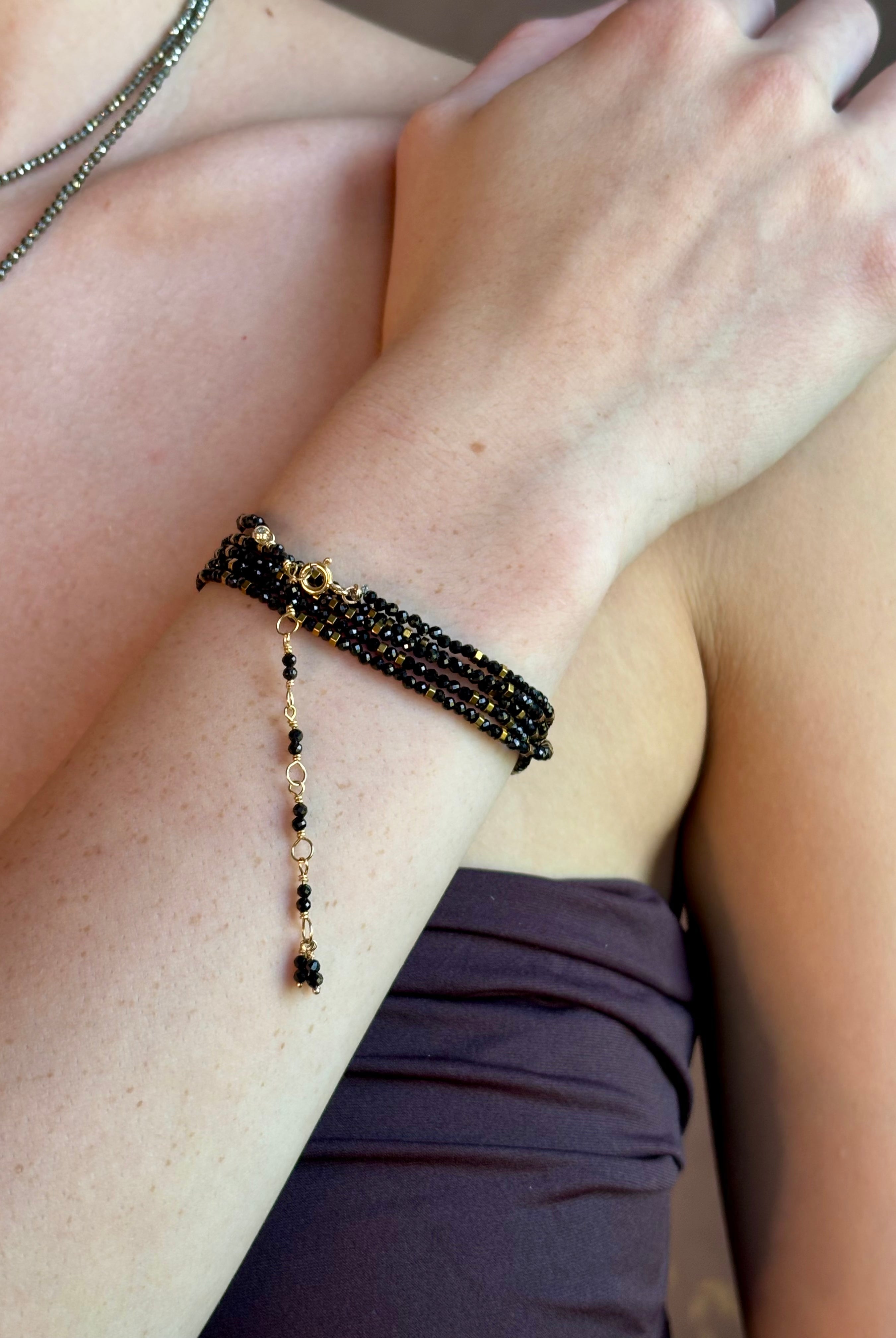 Woman wearing spinel confetti wrap Bracelet from Canadian fine jewelry artist Anne Sportun with natural stone spinel and 18k yellow gold beads that can double as a necklace perfect for travel