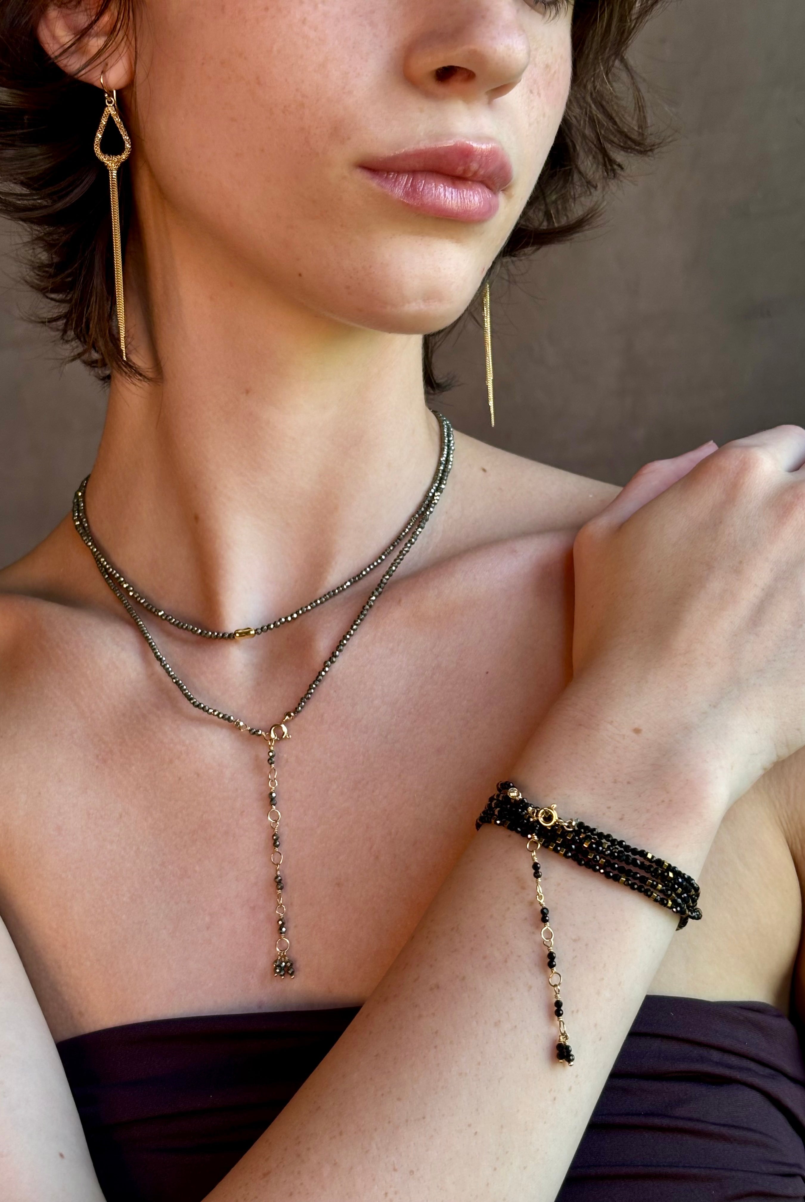 Woman wearing spinel confetti wrap Bracelet from Canadian fine jewelry artist Anne Sportun with natural stone spinel and 18k yellow gold beads that can double as a necklace perfect for travel