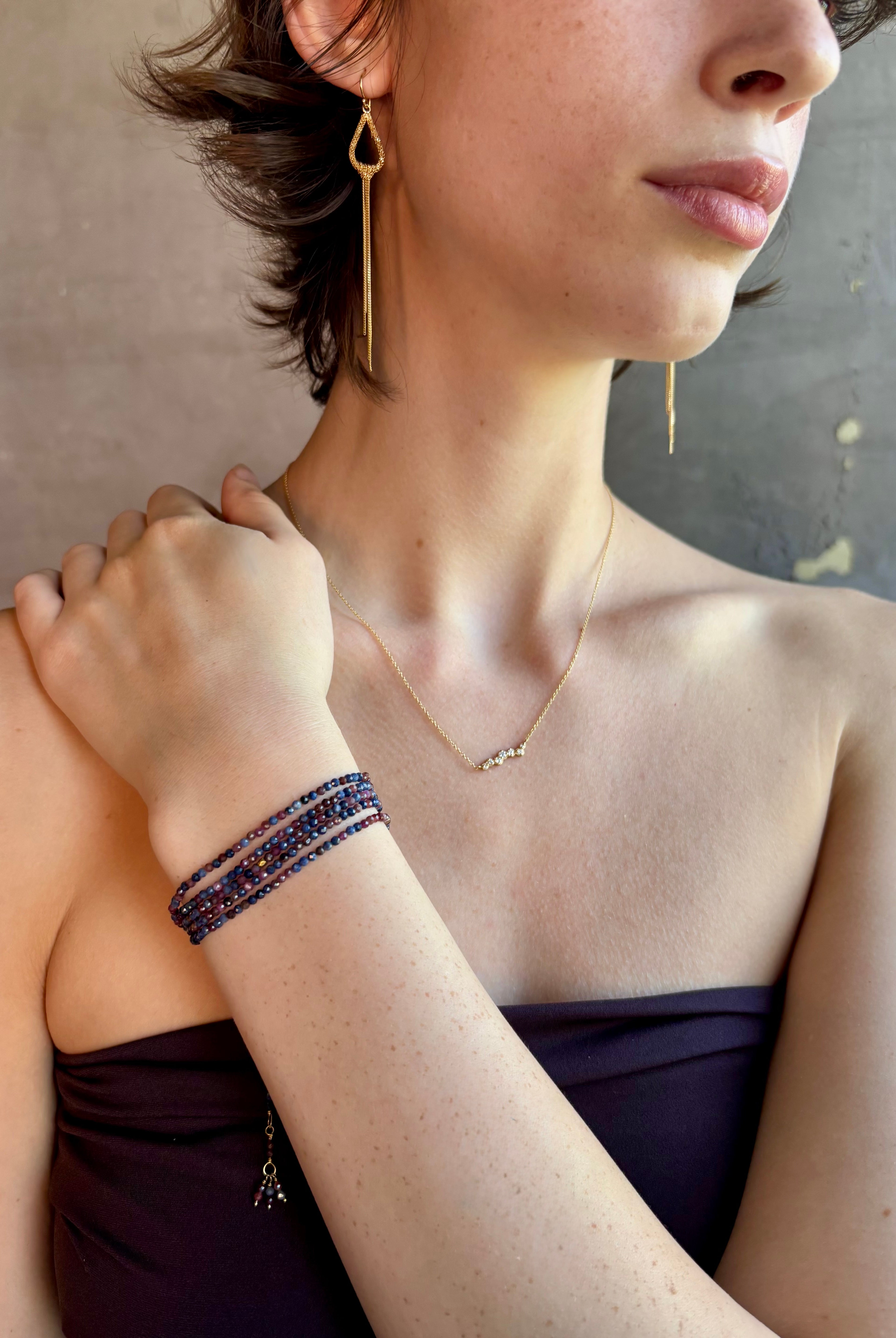 Woman wearing sapphire wrap Bracelet from Canadian fine jewelry artist Anne Sportun with natural multi-colored sapphires and 18k yellow gold that can double as a necklace perfect for travel
