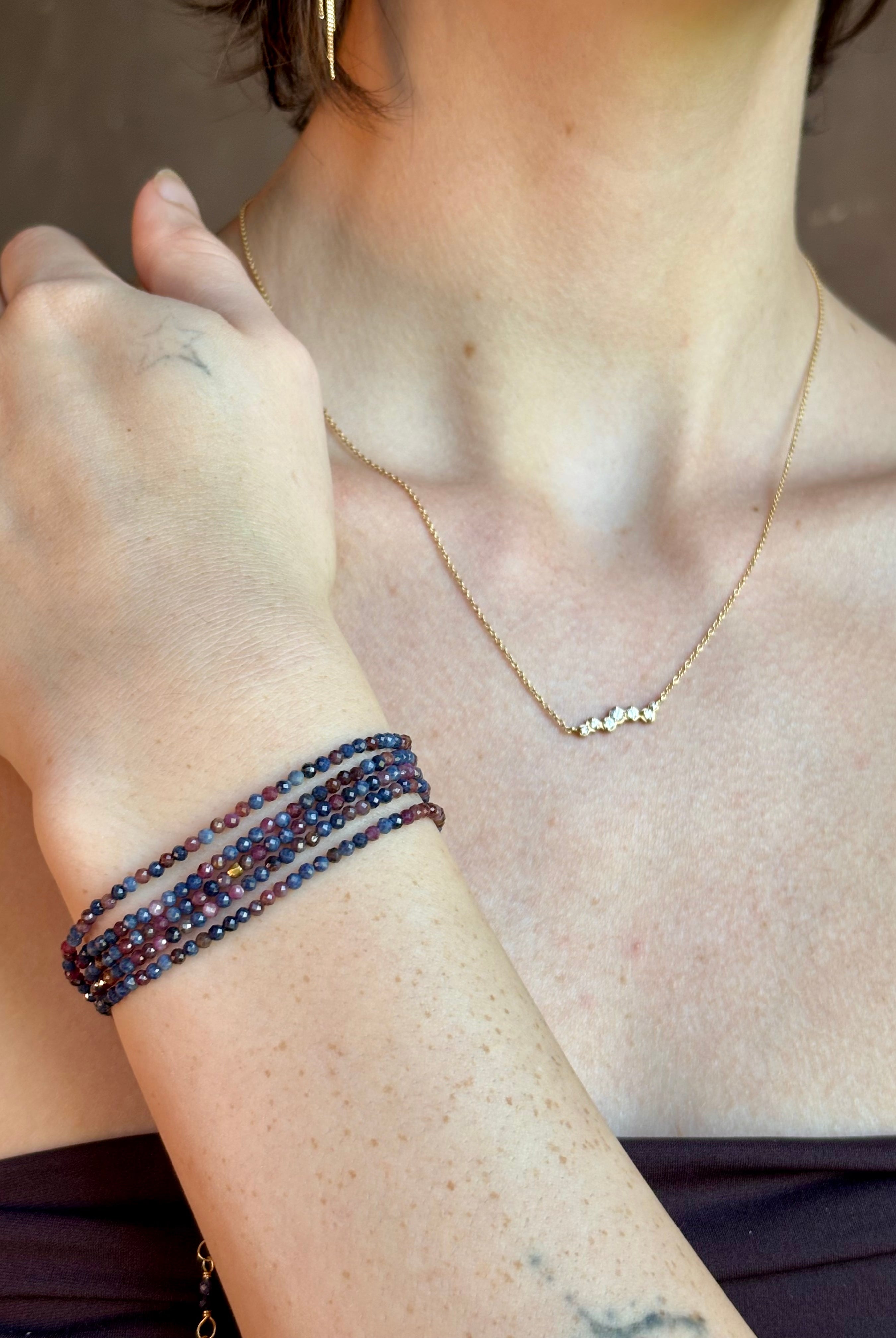 Woman wearing sapphire wrap Bracelet from Canadian fine jewelry artist Anne Sportun with natural multi-colored sapphires and 18k yellow gold that can double as a necklace perfect for travel