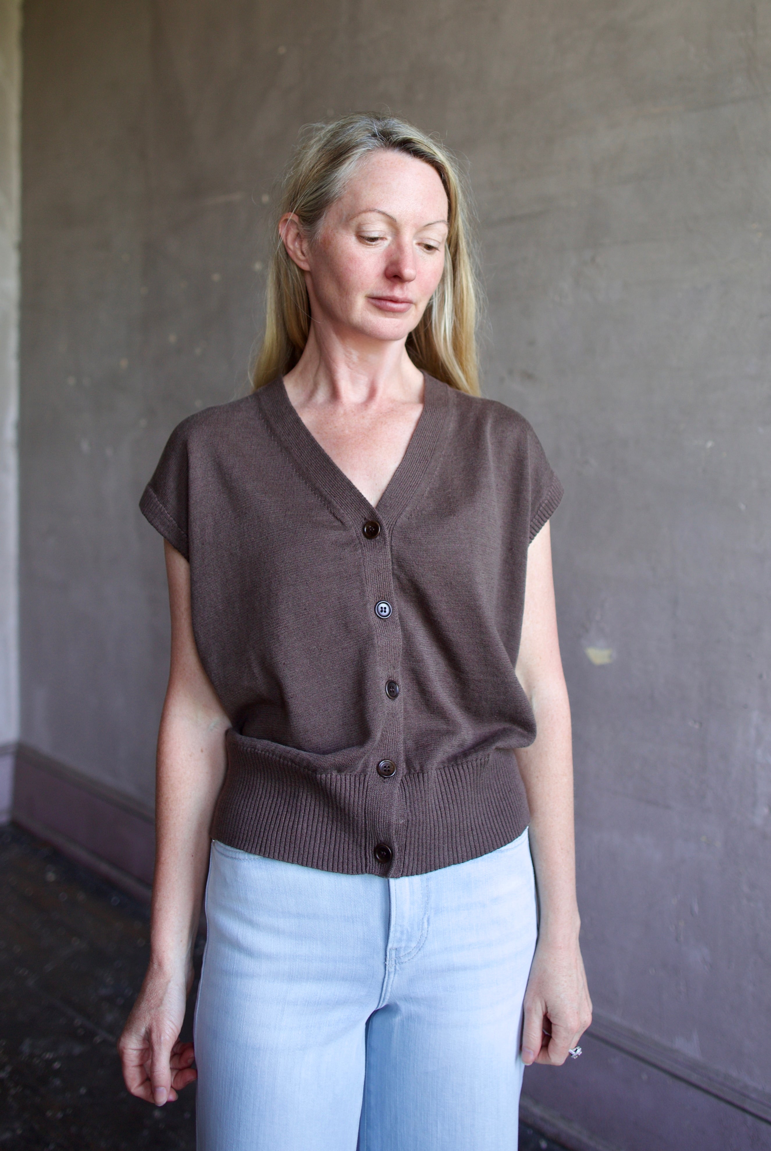 Mature woman wearing the perfect elevated wardrobe staple Apiece Apart Fine Weight linen cotton blend sweater Vest in espresso brown with short sleeves and v- neck