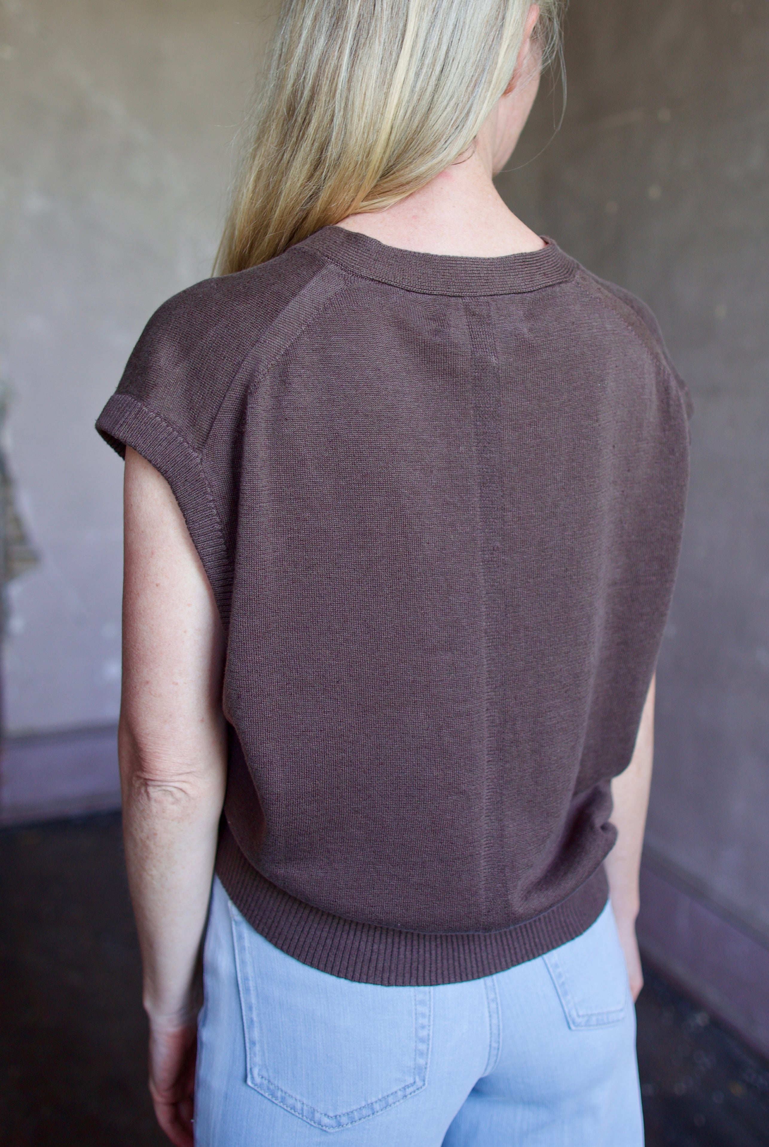 Mature woman wearing the perfect wardrobe staple Apiece Apart Fine Weight linen cotton blend sweater Vest in espresso brown with short sleeves and v- neck