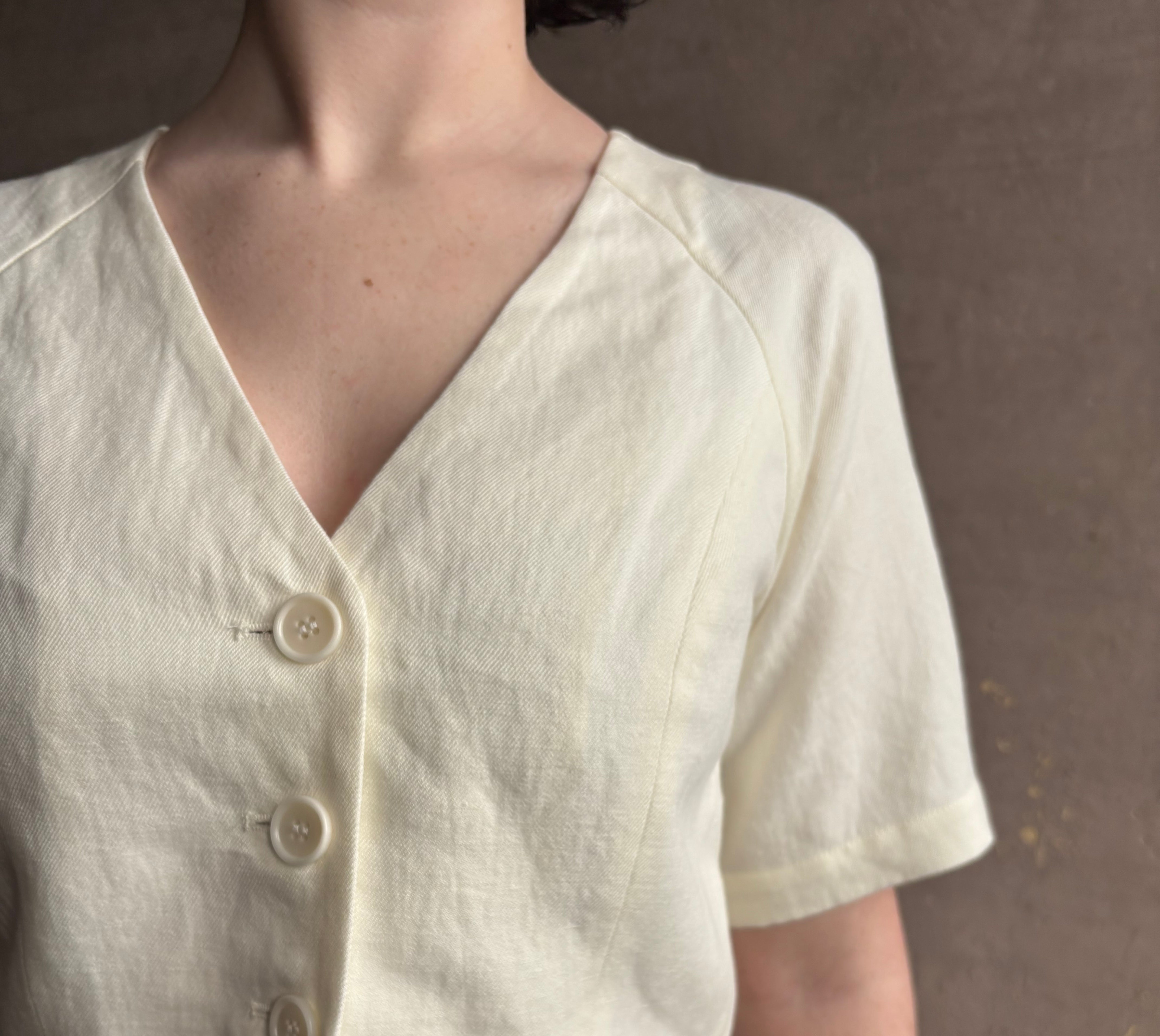 Woman wearing an elevated cream Lia designer Crop Top from Apiece Apart with short sleeves and v- neck