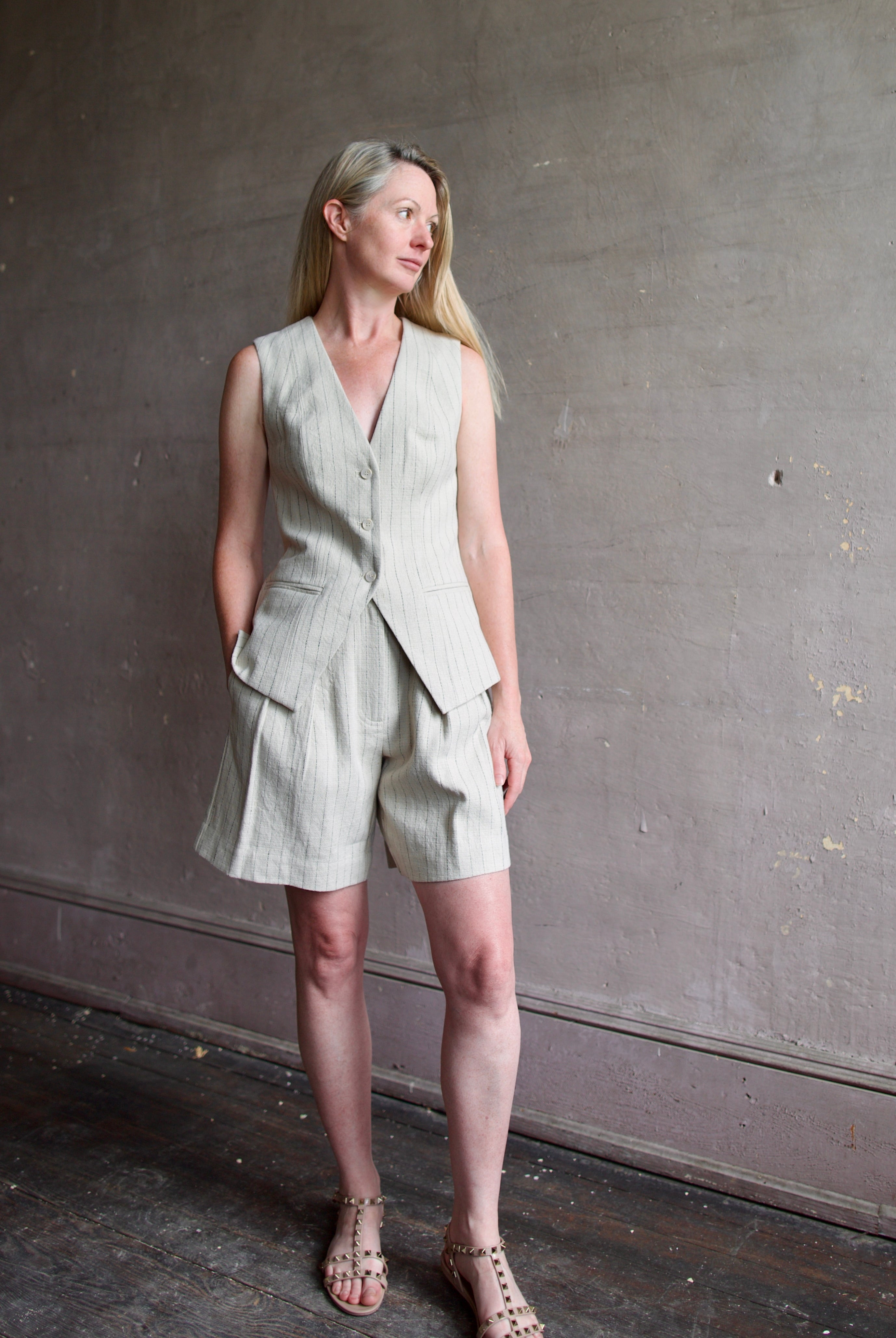 Mature woman wearing luxury brand Apiece Apart Helena Vest and Linaza Shorts in linen with expert sustainable craftsmanship, refined tailoring and long inseam