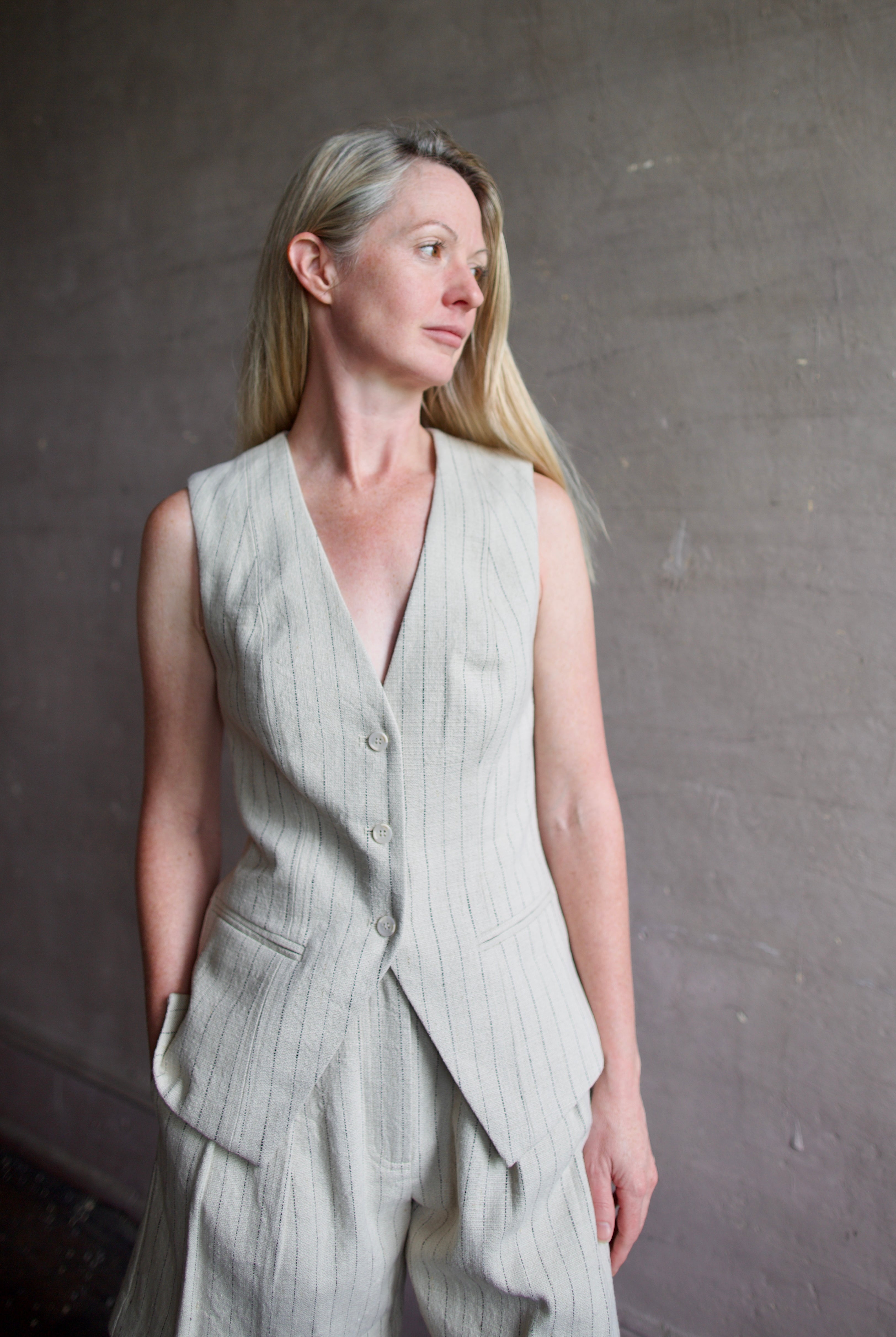 Mature woman wearing luxury brand Apiece Apart Helena Vest and Linaza Shorts in linen with expert sustainable craftsmanship, refined tailoring and long inseam