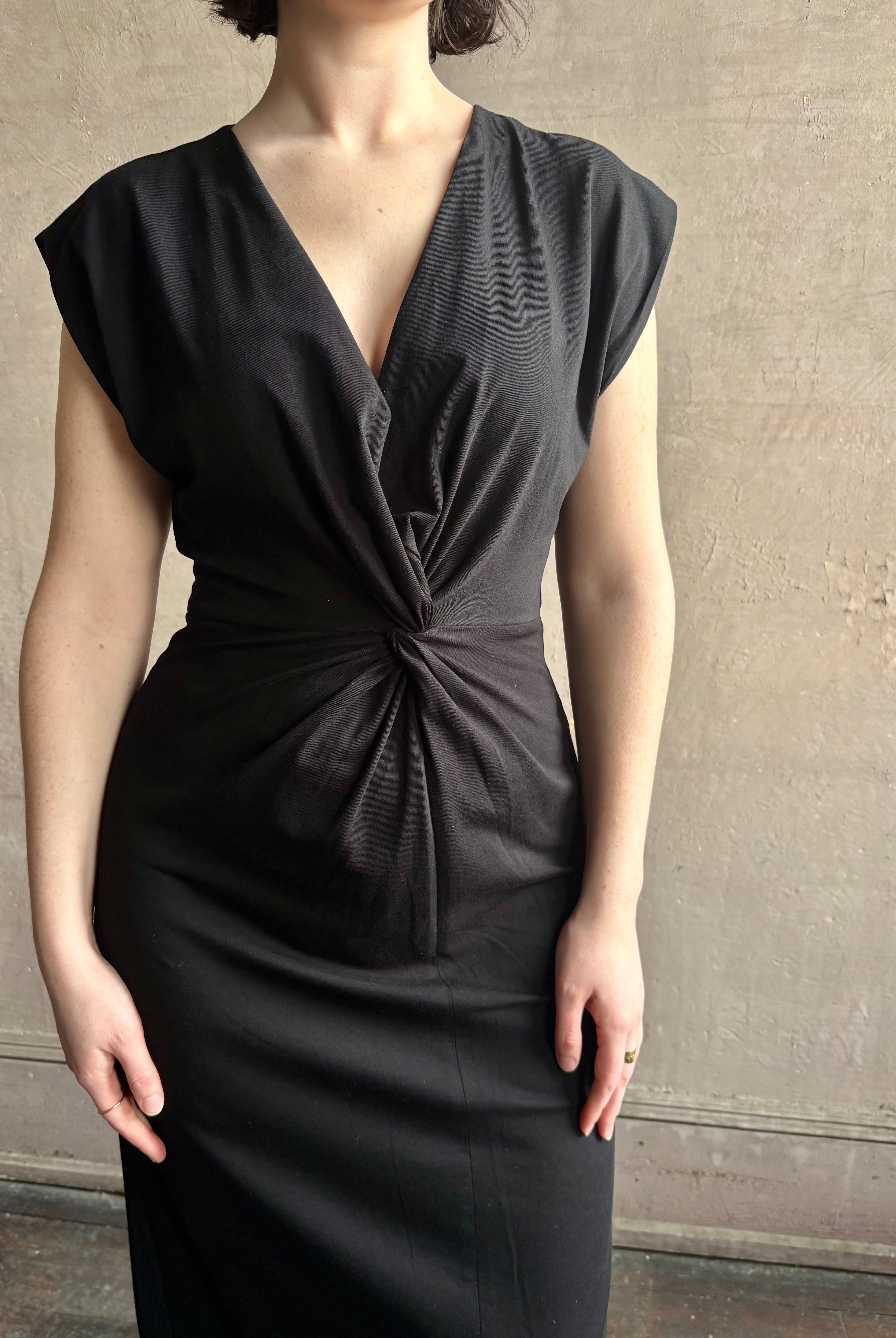 Woman wearing a timeless Twist Front Column Dress from Apiece Apart in a comfortable black cotton jersey midi that can transition day to night