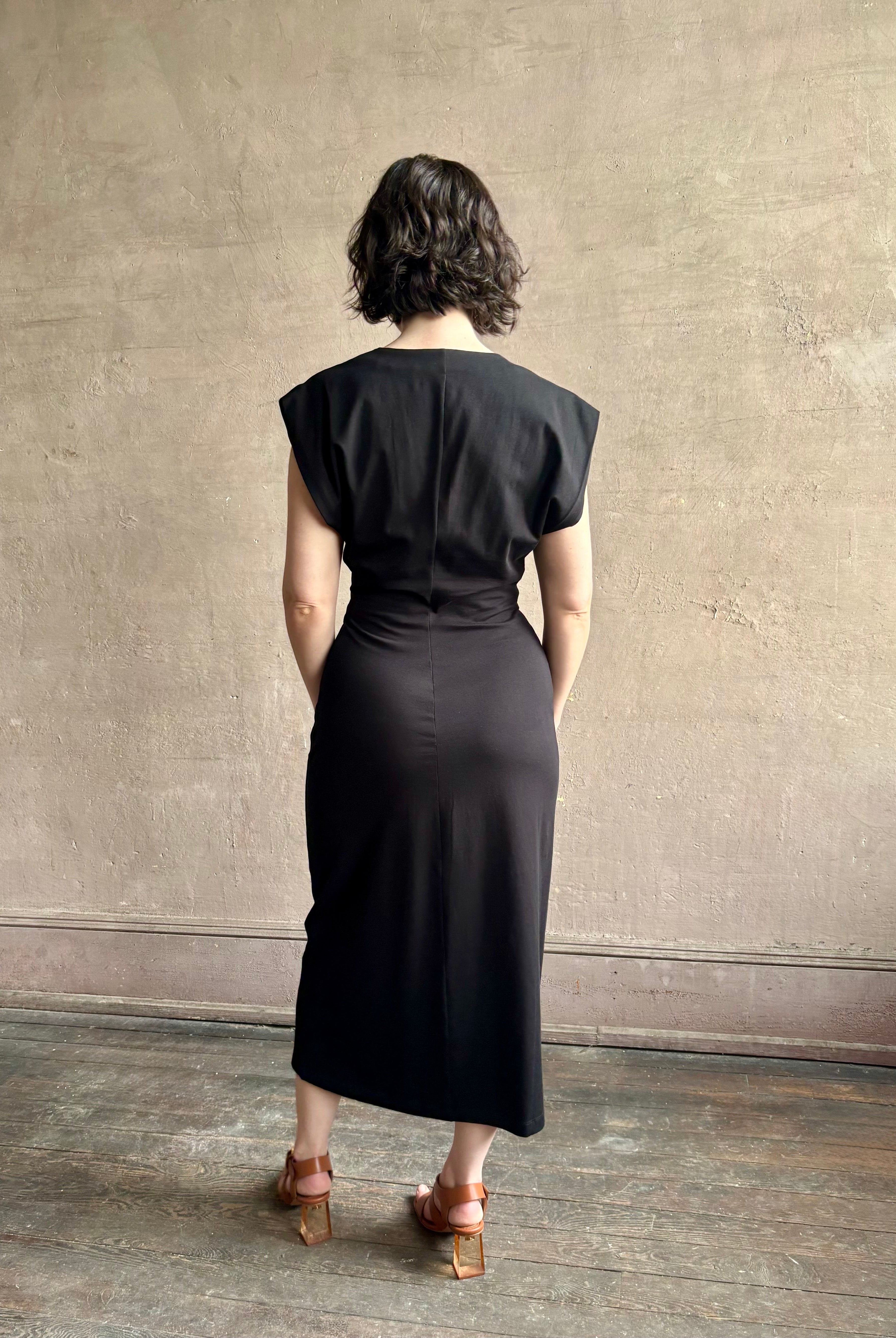 Woman wearing a timeless Twist Front Column Dress from Apiece Apart in a comfortable black cotton jersey midi that can transition day to night