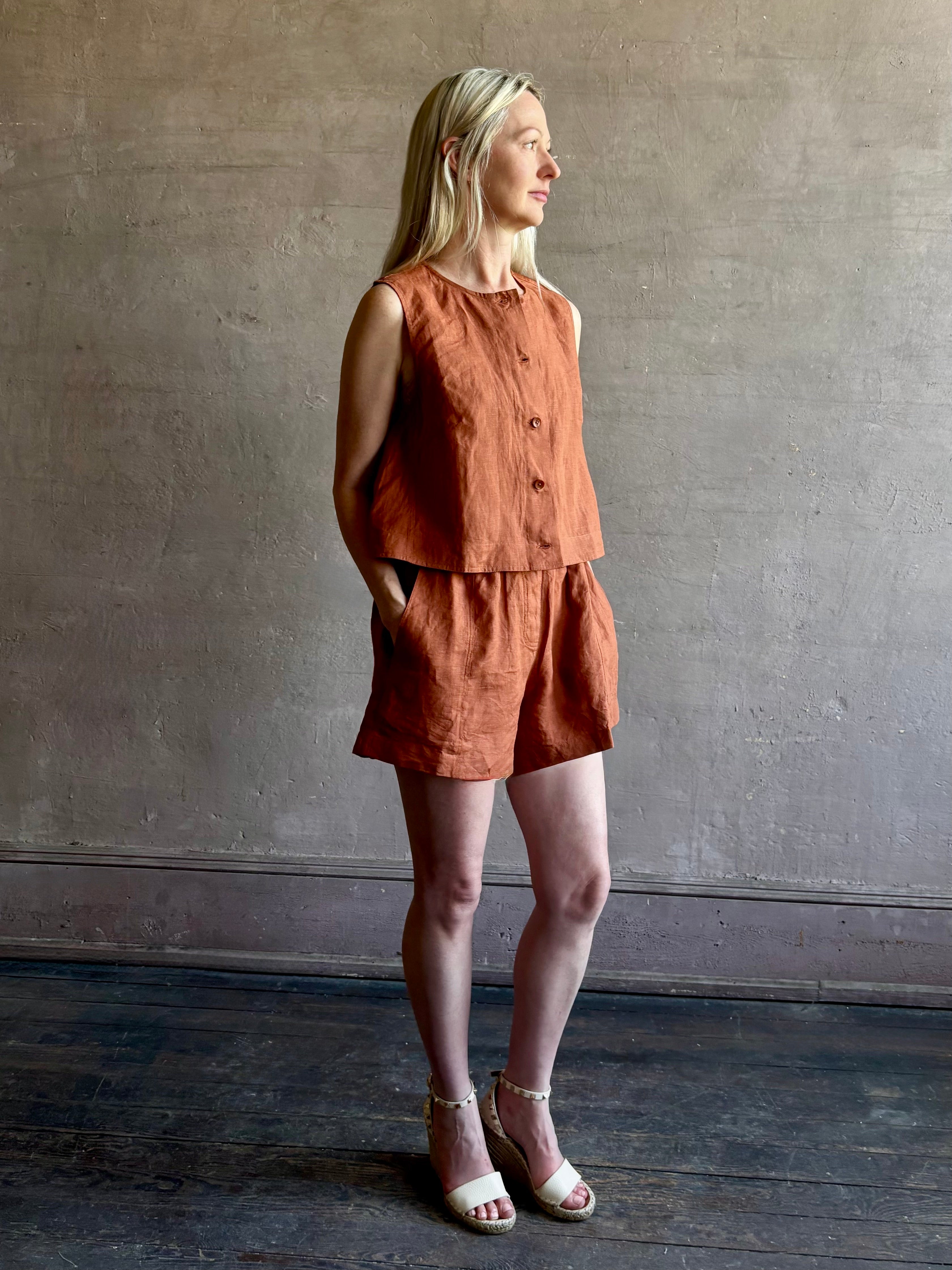 Mature woman wearing the Mar Short from Apiece Apart rendered in a rust hue and crafted from 100% linen with an adjustable elastic waistband and pockets and matching top set