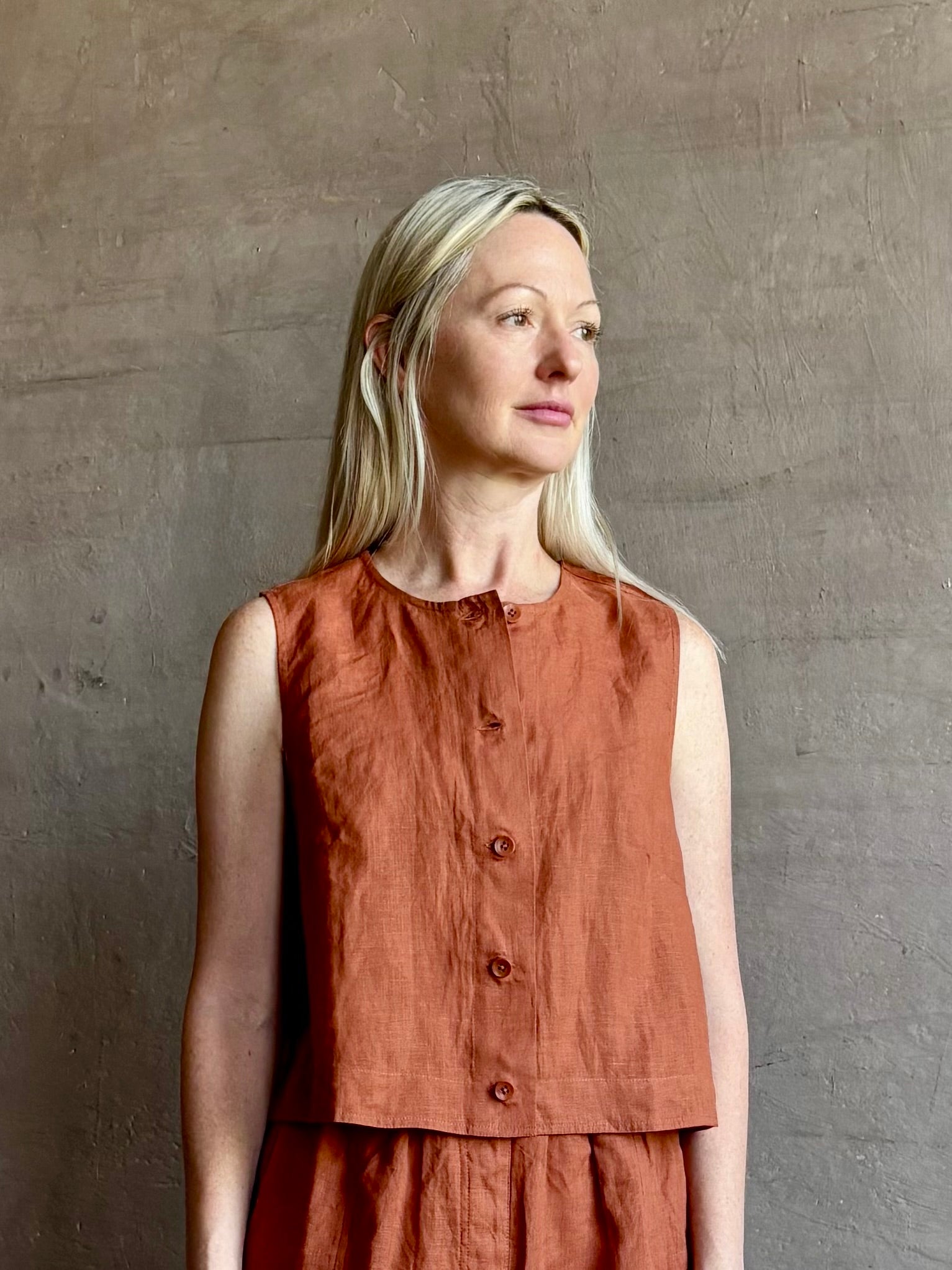 Mature woman wearing the Mar Short from Apiece Apart rendered in a rust hue and crafted from 100% linen with an adjustable elastic waistband and pockets and matching top set