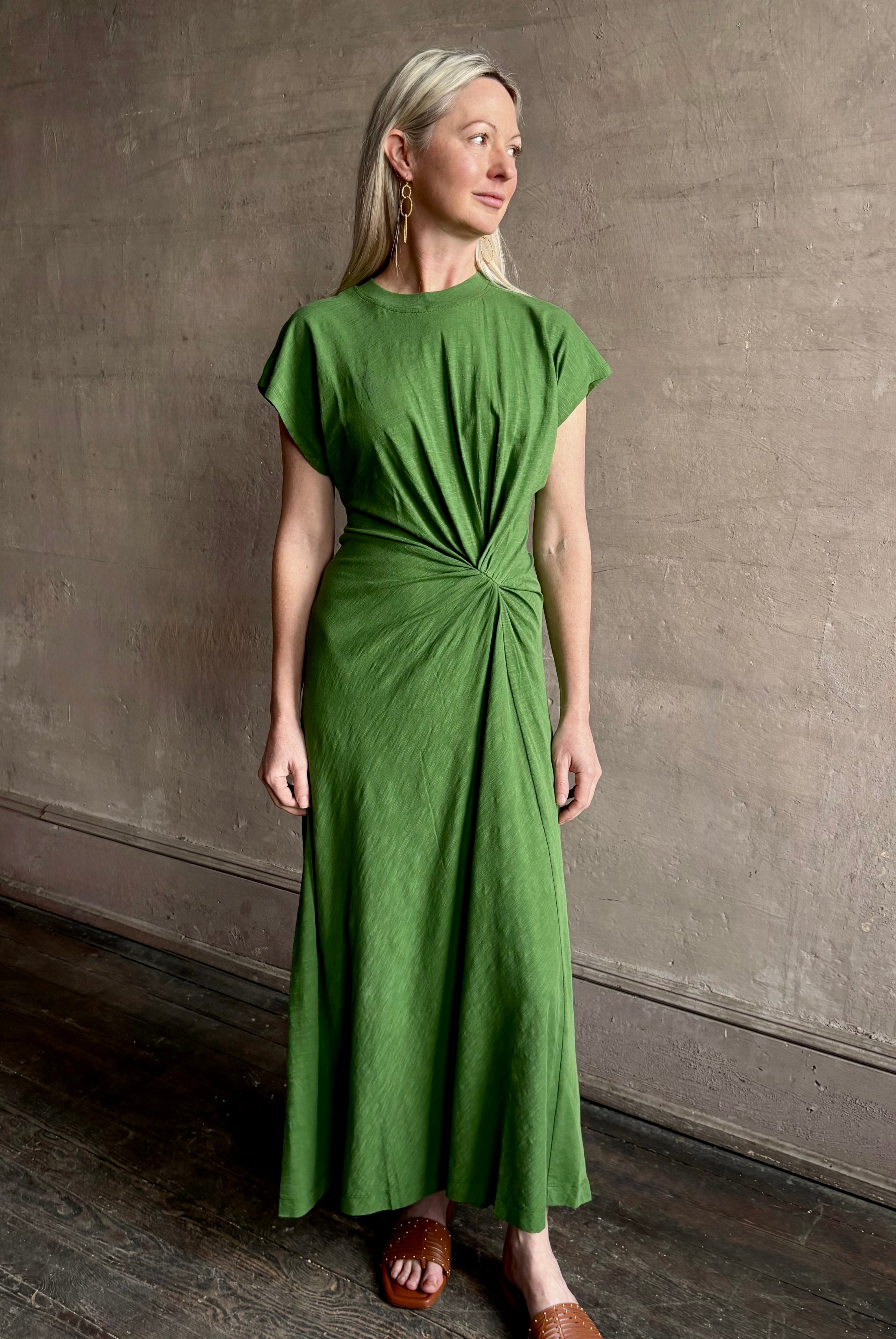 Mature woman wearing Volta Twist maxi Dress from Apiece Apart in a comfy green organic cotton jersey with short sleeves and crew neck