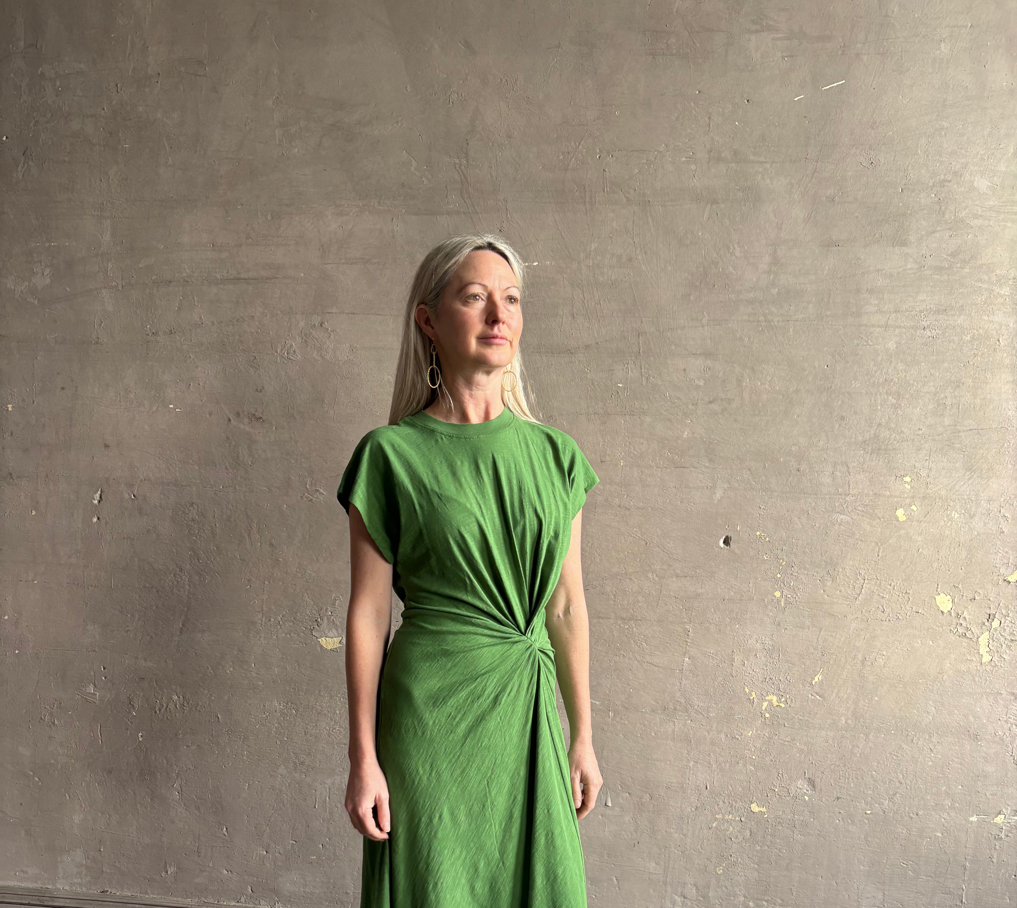 Mature woman wearing Volta Twist maxi Dress from Apiece Apart in a comfy green organic cotton jersey with short sleeves and crew neck