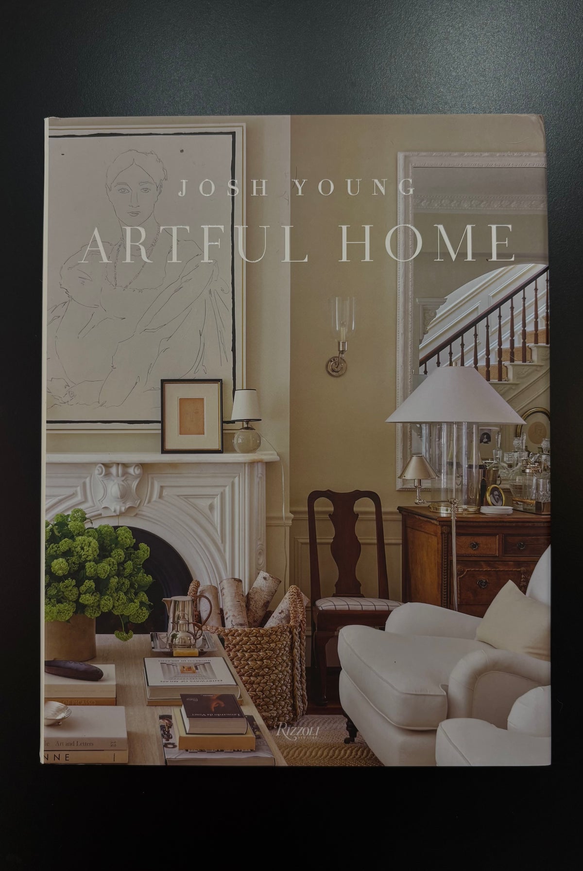 book cover of 'Artful Home' by Josh Young, featuring a warm-toned classic living room with a fireplace, armchair, and desk.