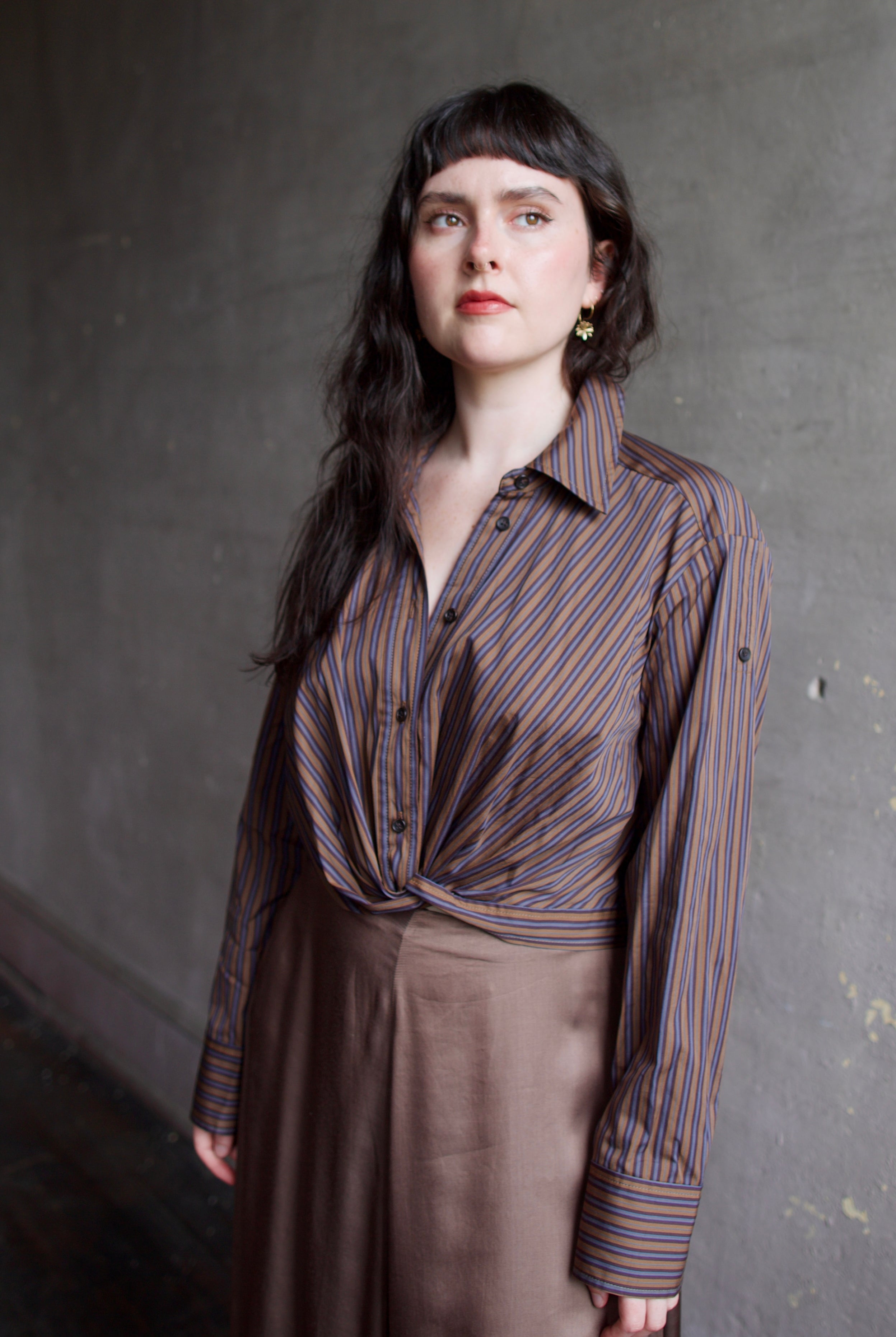 Model wearing the cotton ALC Leo button down shirt with brown and blue stripes and crop twist front