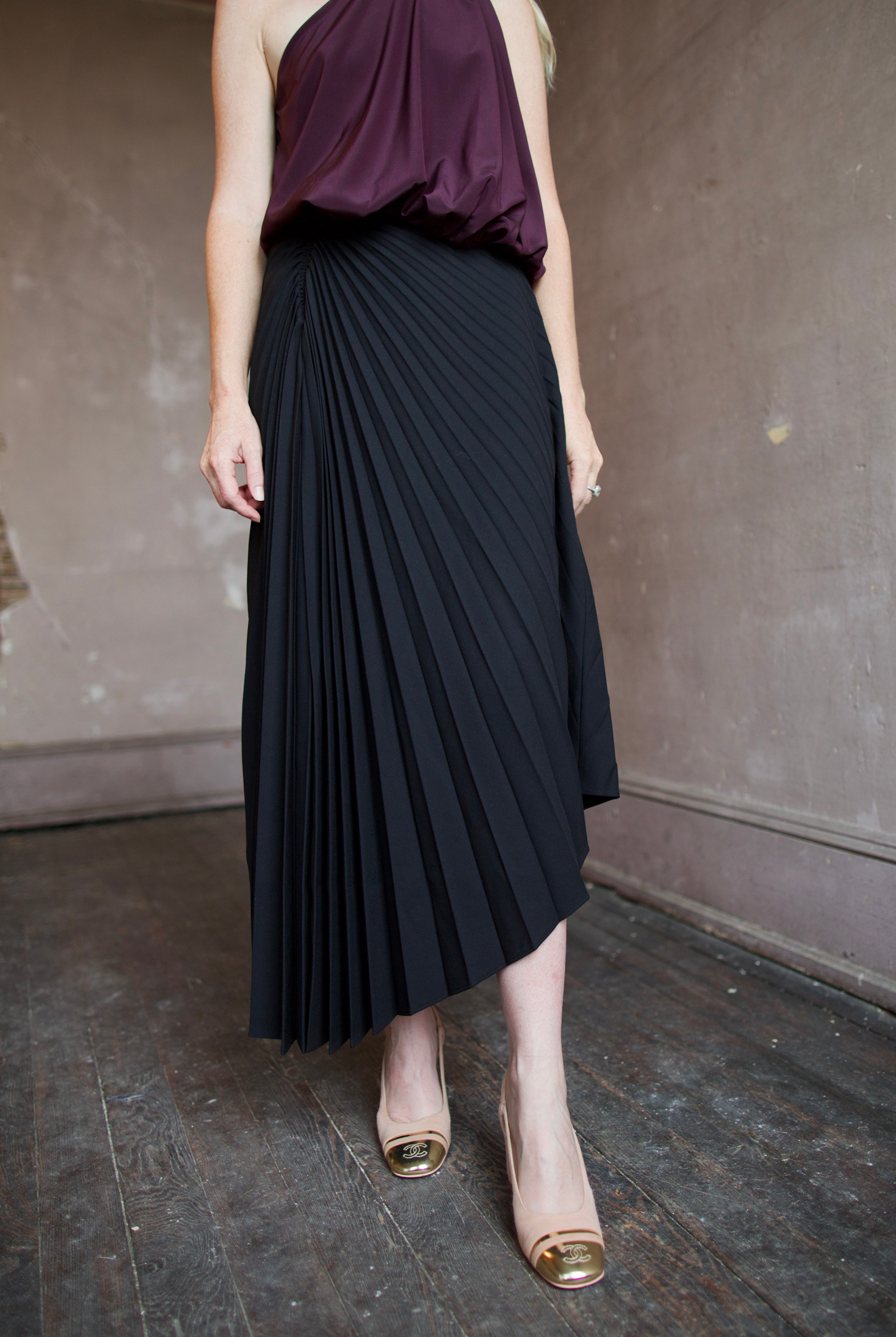 Model wearing a black pleated wool skirt and elevated date night purple top by ALC