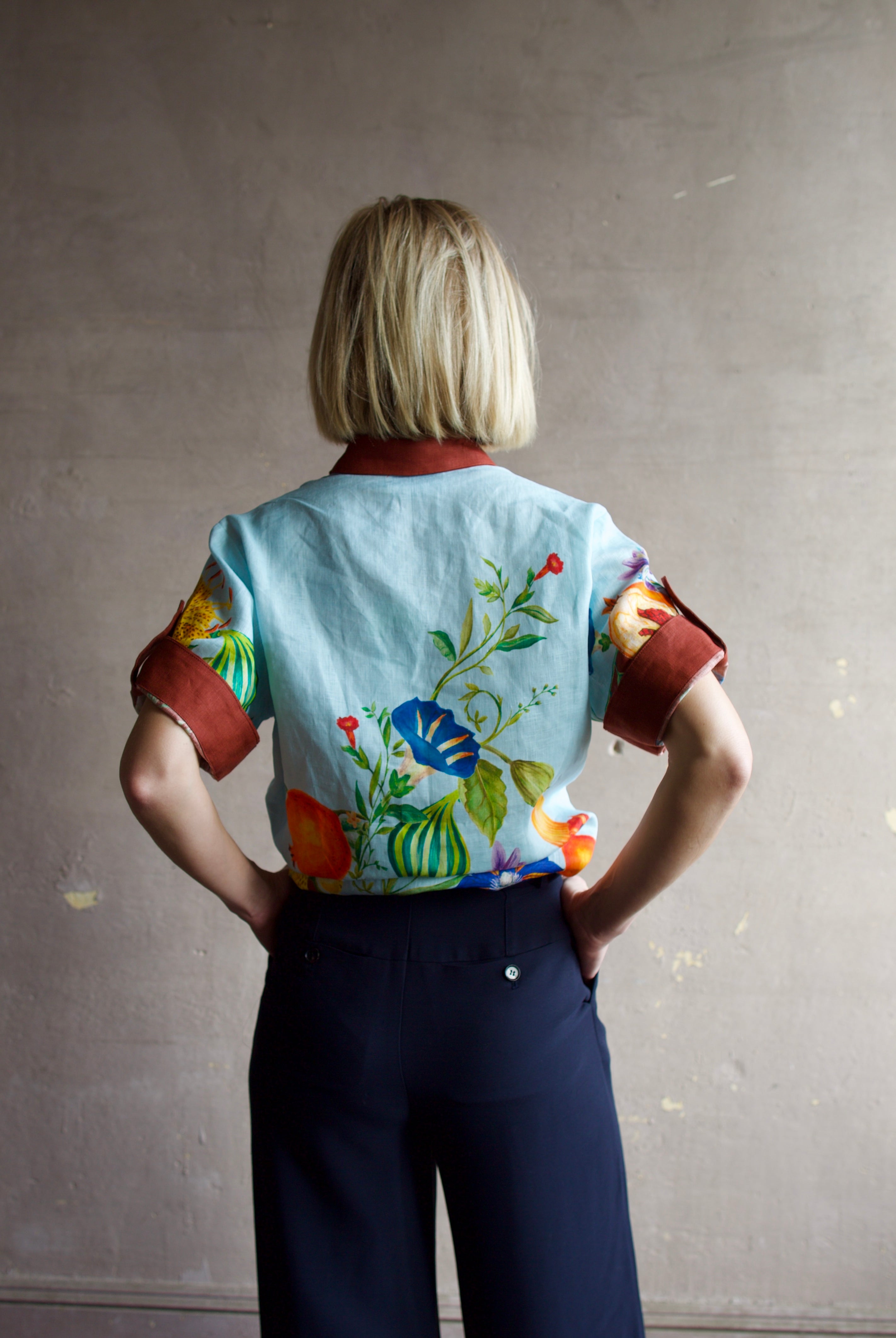 Image of the back of a woman wearing the Alemais Dahlia top, Ulla Johnson Gia Belt and Apiece Apart Cara Wide leg trousers.