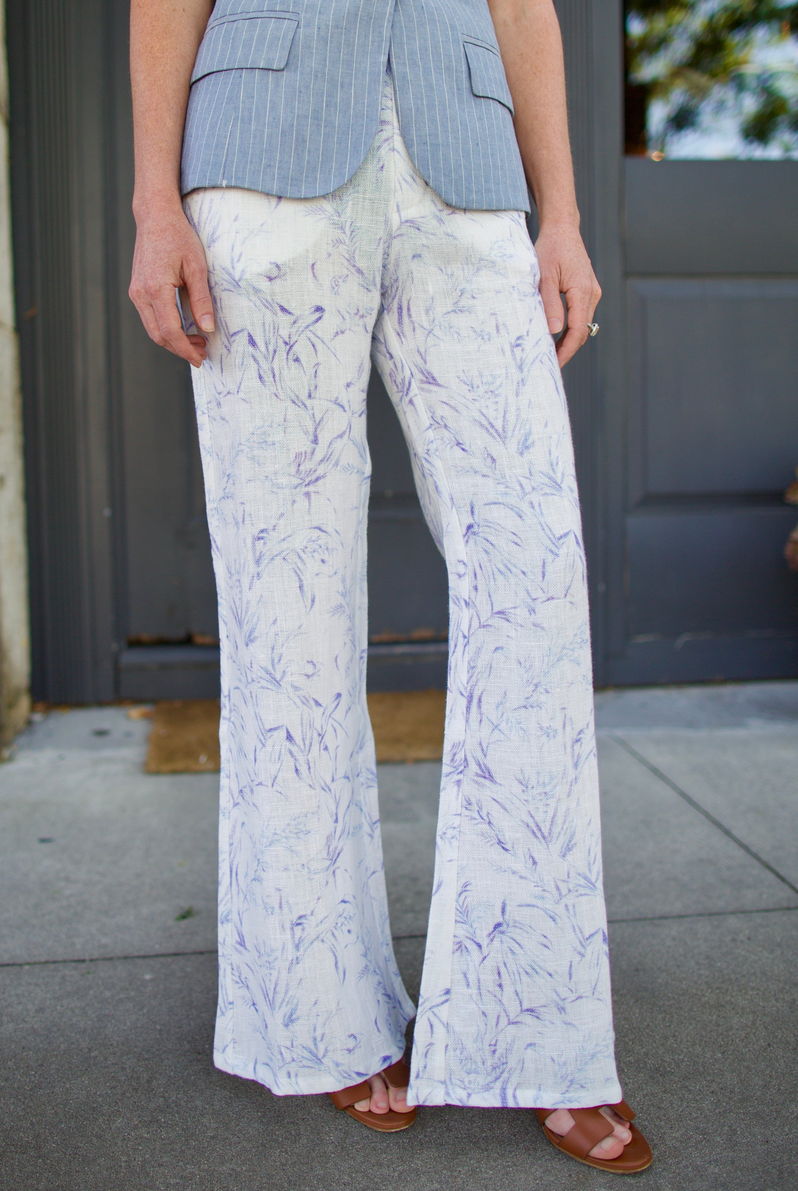 Woman wearing luxury designer Alix of Bohemia bunny toile linen trousers in white with blue print flare high rise