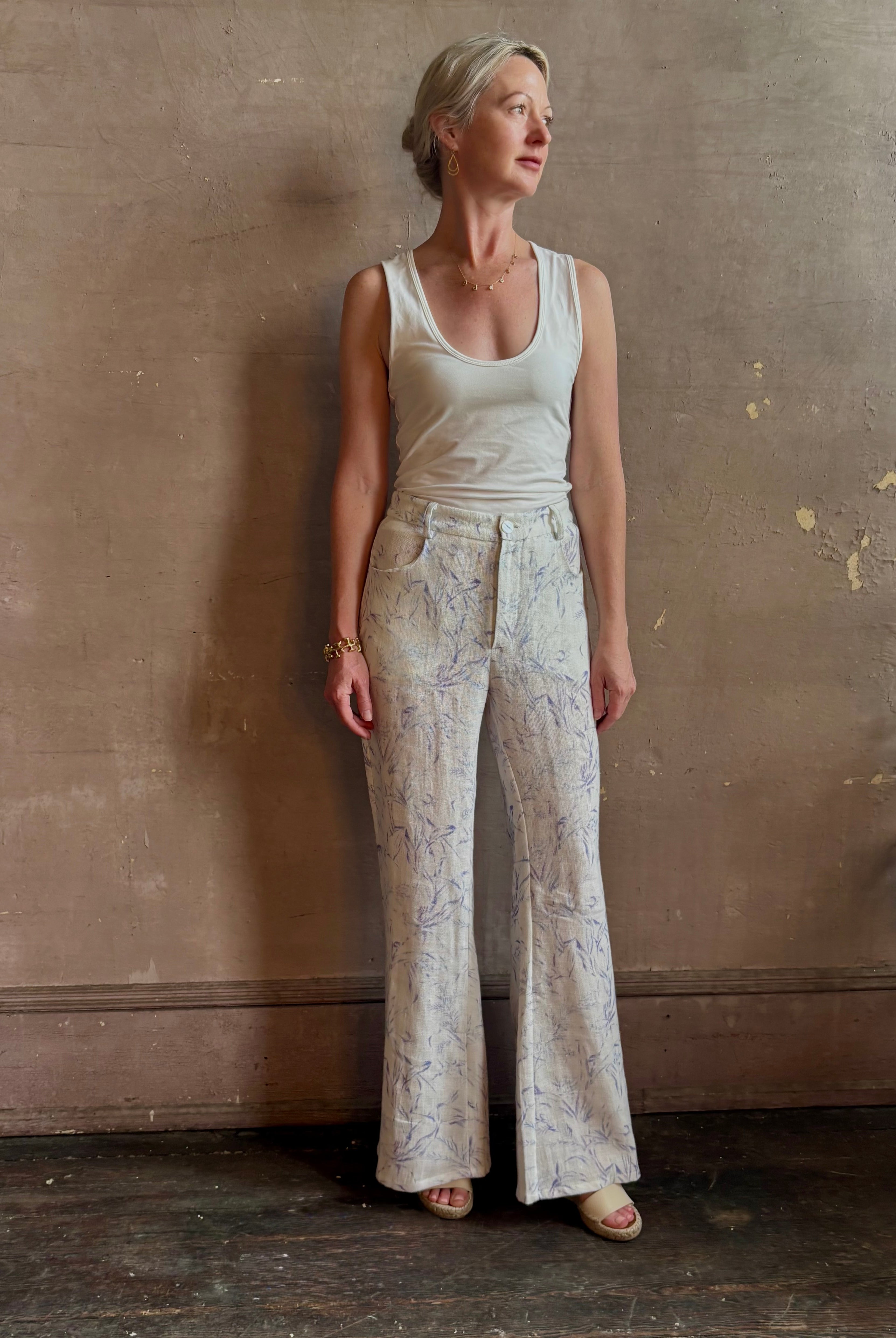 Woman wearing luxury designer Alix of Bohemia bunny toile linen trousers in white with blue print flare high rise
