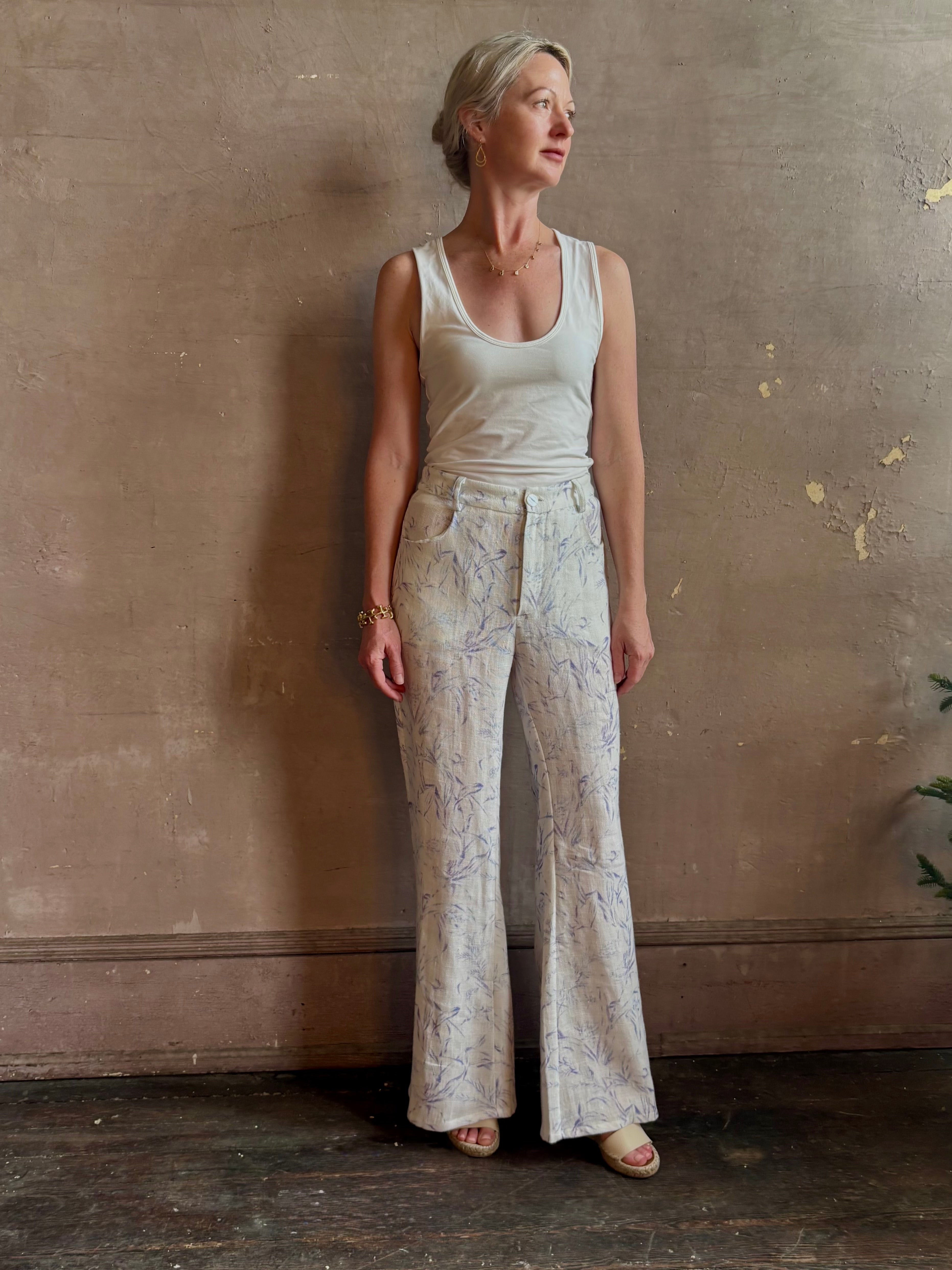 Woman wearing luxury designer Alix of Bohemia bunny toile linen trousers in white with blue print flare high rise