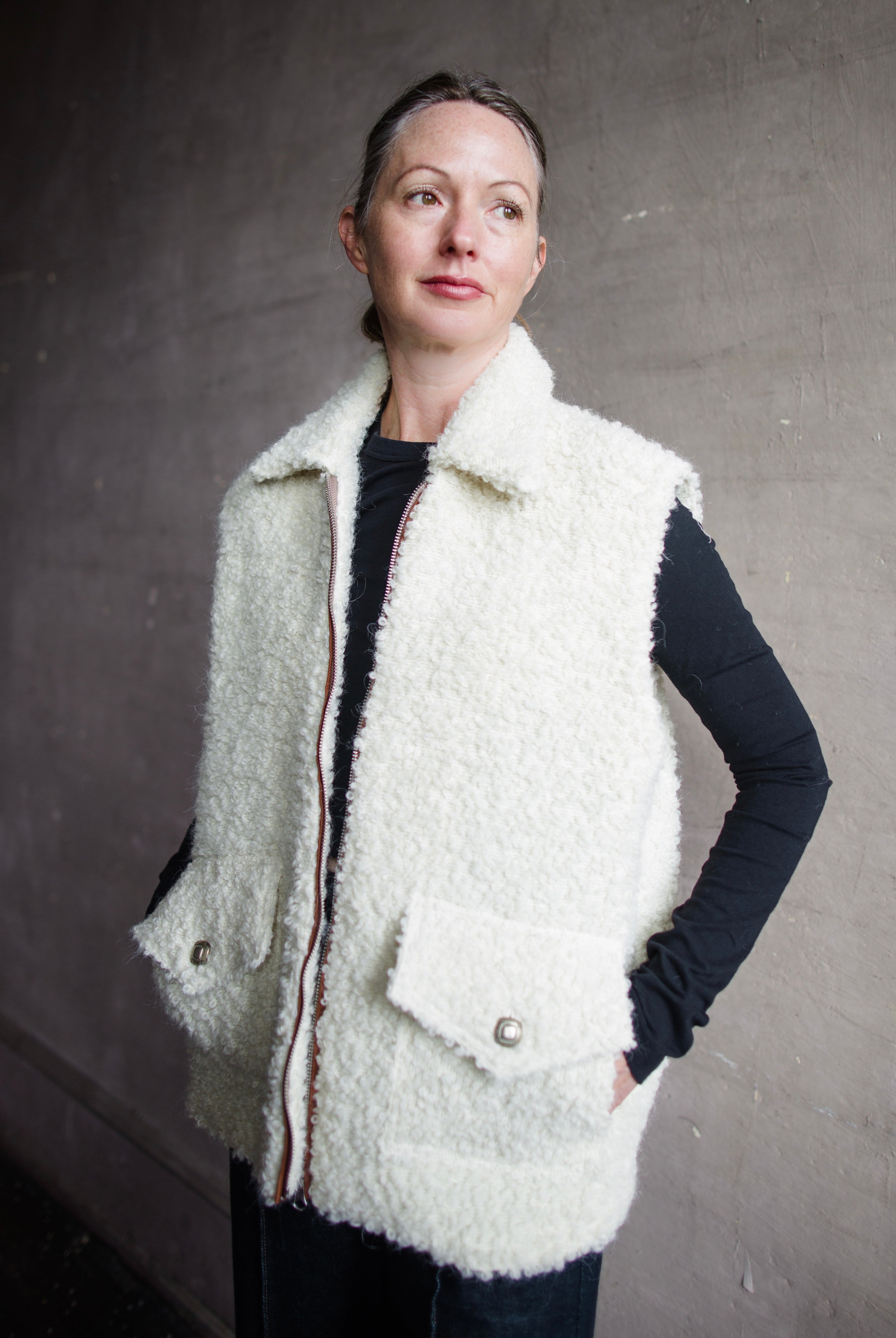 Image featuring a woman wearing the Alix of Bohemia Mickey Suri wool vest knitted with Italian alpaca wool in cream with front pockets with flaps and integral side seam pockets.