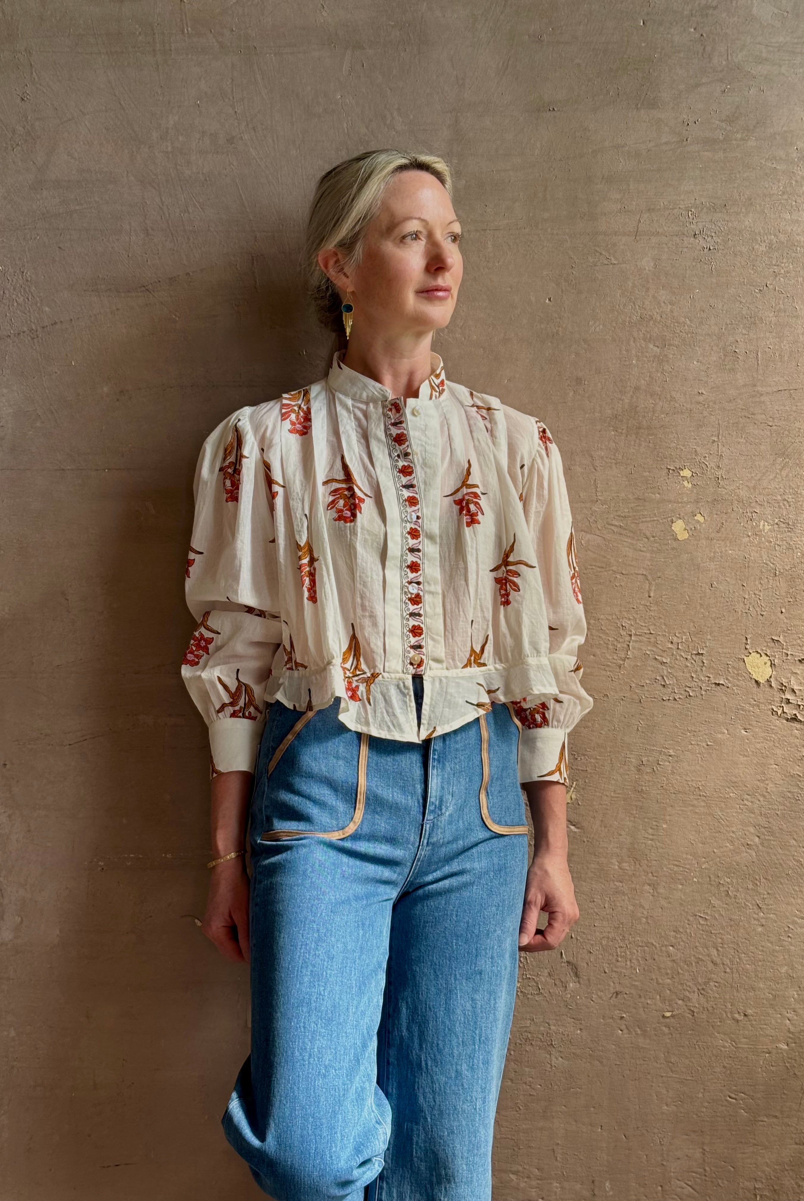 Mature woman wearing Alix of Bohemia Ryland Persimmon Flower Shirt with beautiful pin tucking and gathered waist detail at back, long sleeves, mandarin collar, and cropped top