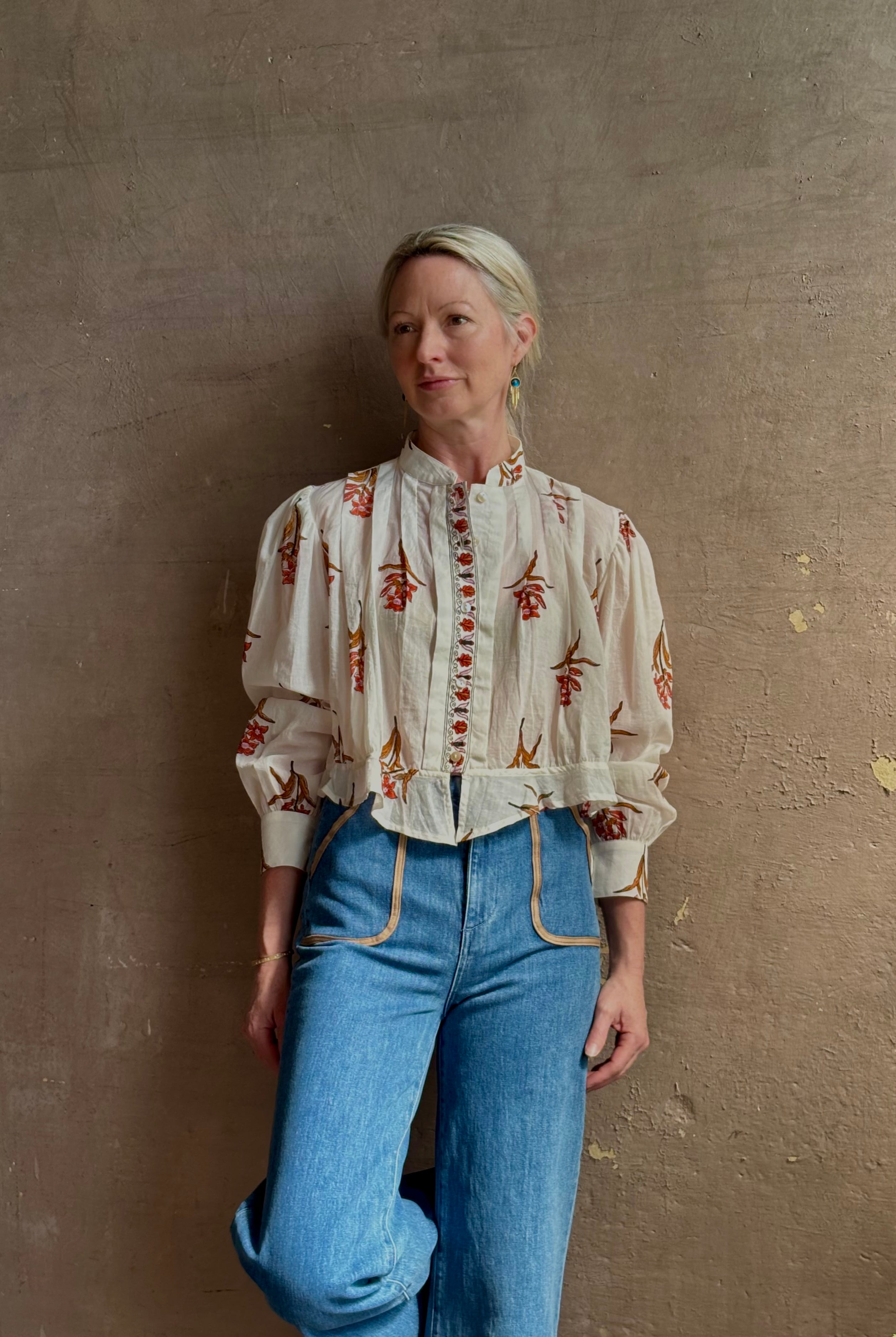 Mature woman wearing Alix of Bohemia Ryland Persimmon Flower Shirt with beautiful pin tucking and gathered waist detail at back, long sleeves, mandarin collar, and cropped top