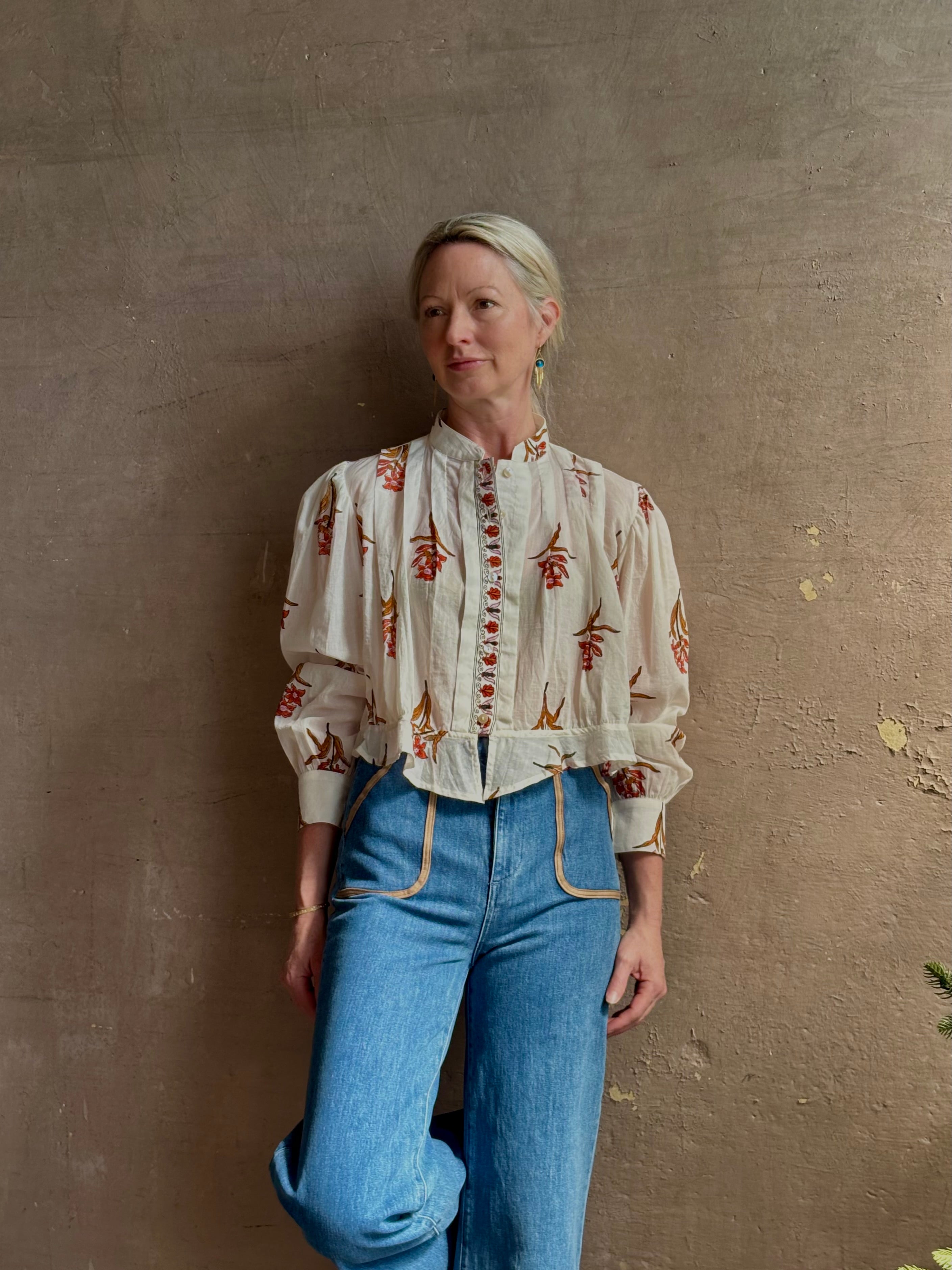 Mature woman wearing Alix of Bohemia Ryland Persimmon Flower Shirt with beautiful pin tucking and gathered waist detail at back, long sleeves, mandarin collar, and cropped top