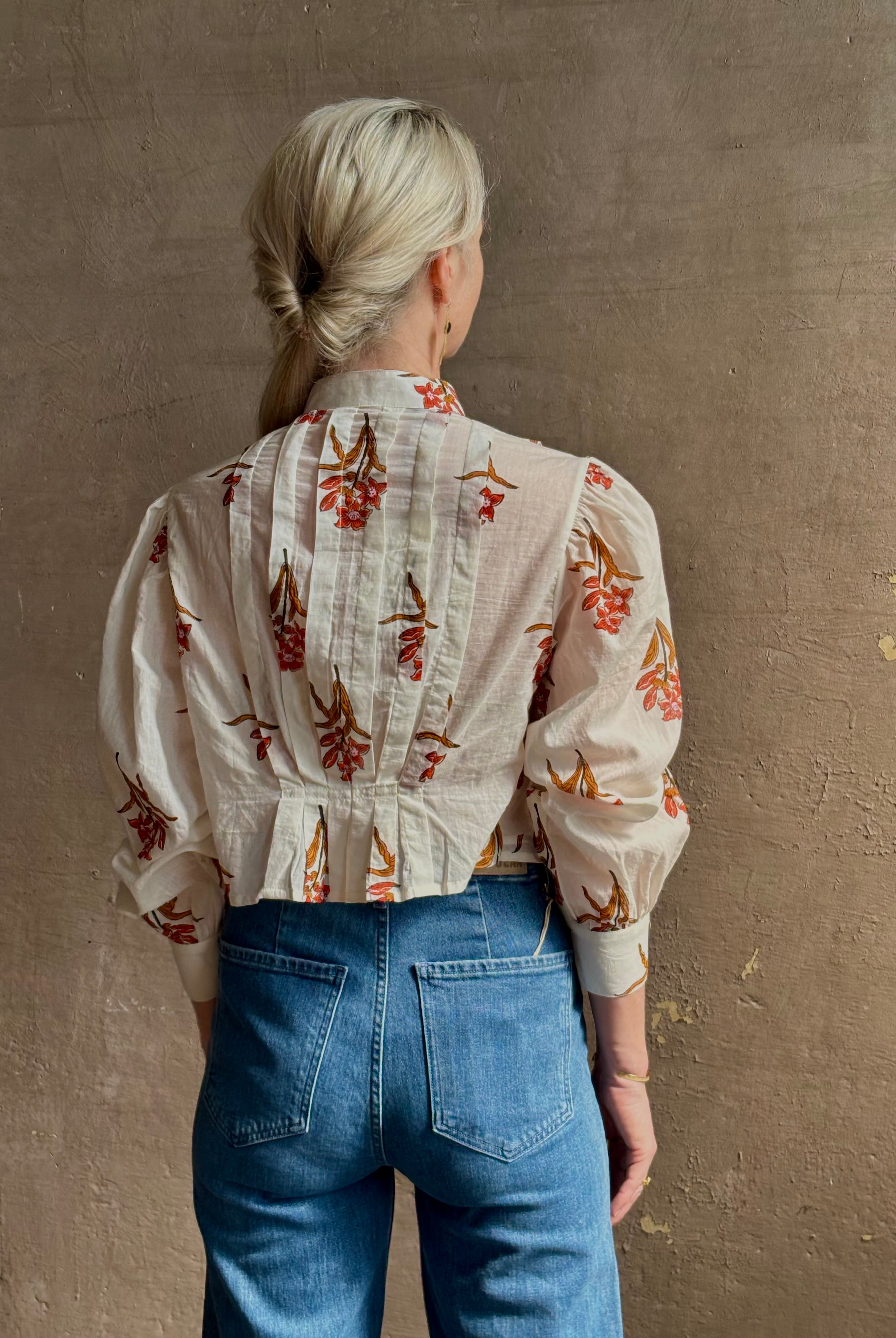 Mature woman wearing Alix of Bohemia Ryland Persimmon Flower Shirt with beautiful pin tucking and gathered waist detail at back, long sleeves, mandarin collar, and cropped top