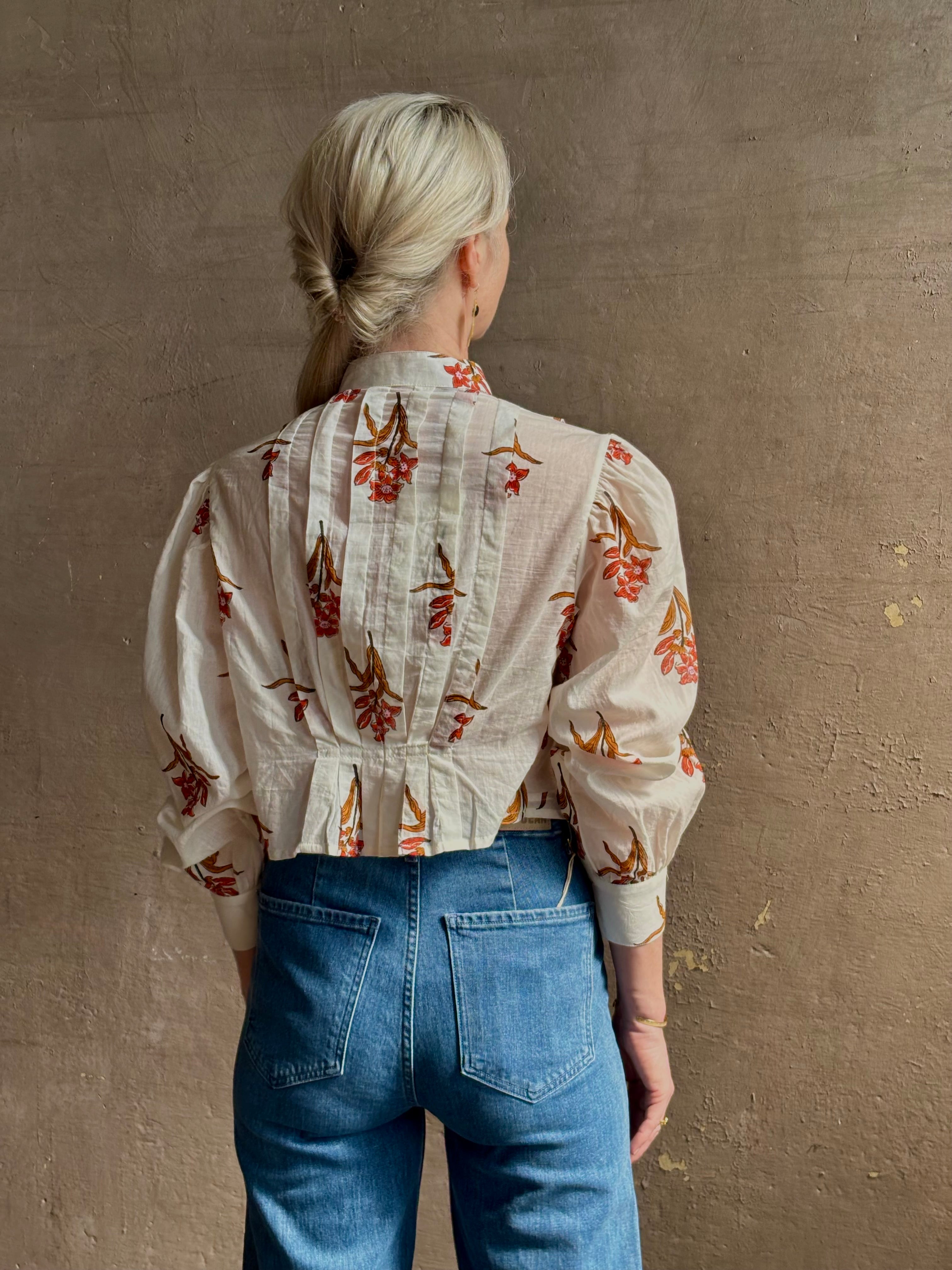 Mature woman wearing Alix of Bohemia Ryland Persimmon Flower Shirt with beautiful pin tucking and gathered waist detail at back, long sleeves, mandarin collar, and cropped top