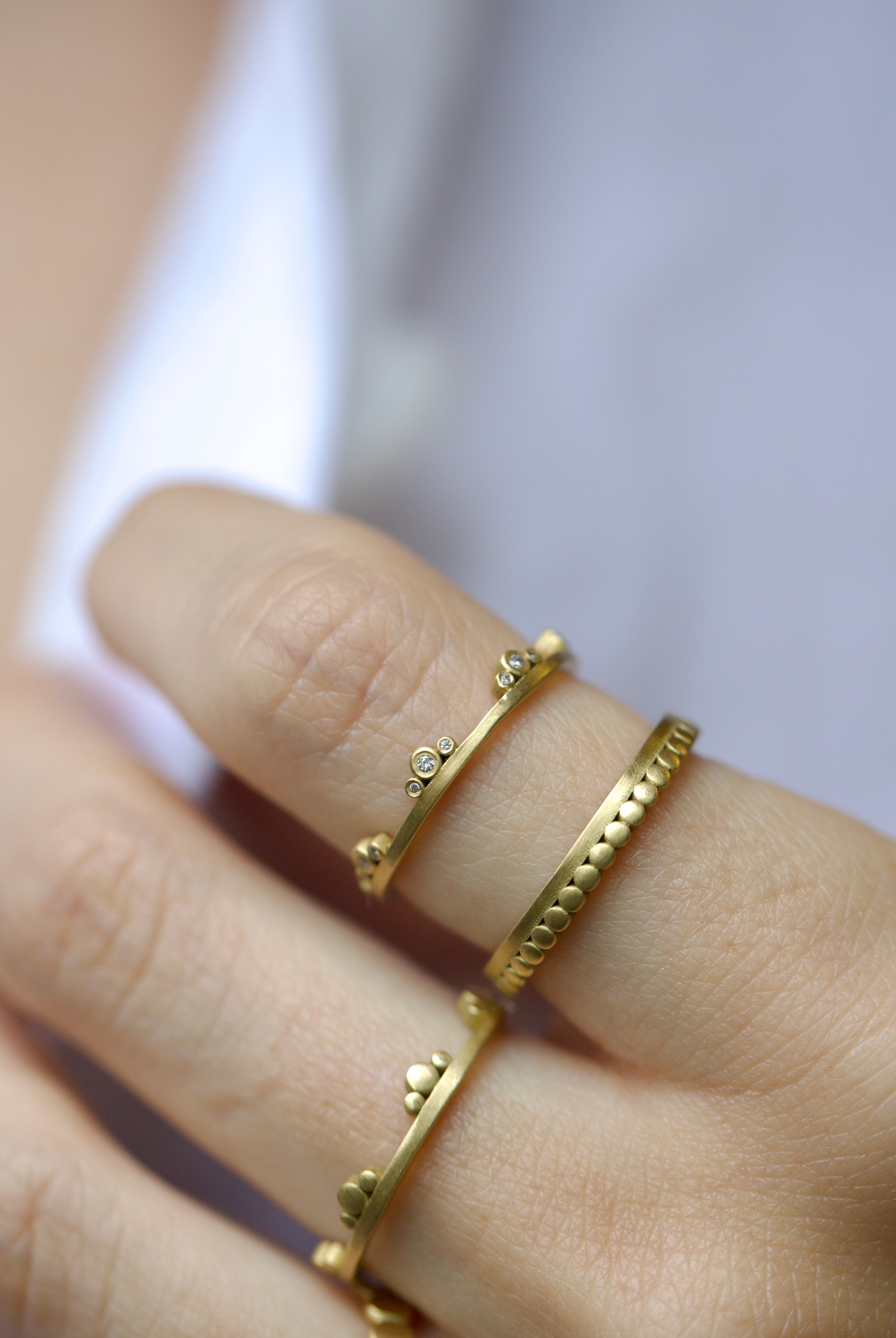 Image of American Jeweler Ananda Khalsa Diamond Side Trio 18k gold matte finish ring with seven 1mm white diamond trio encircling arrangement