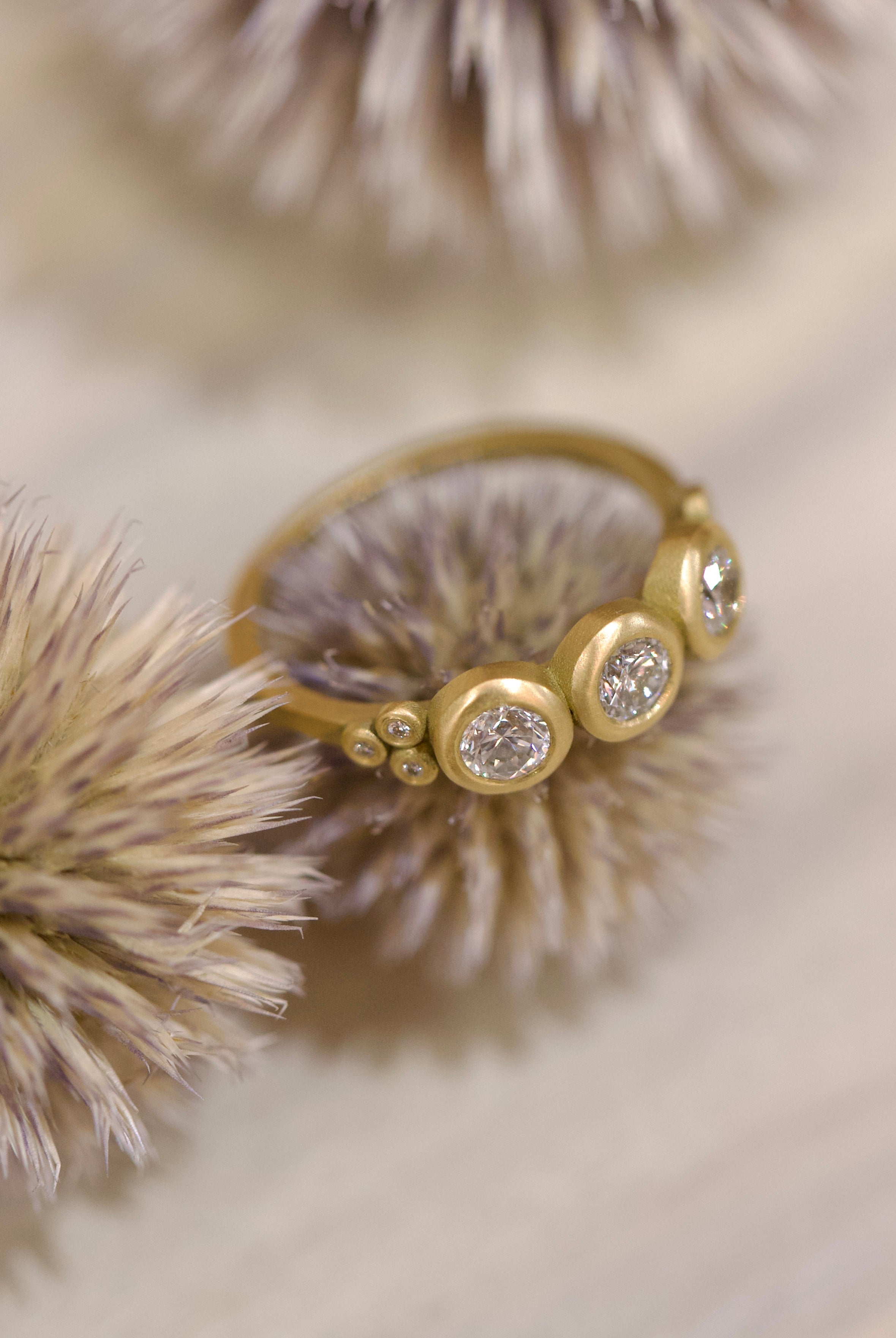Image of Ananda Khalsa luxury handmade 18k hammered matte gold ring with three 4mm brilliant cut white diamonds delivering timeless elegance