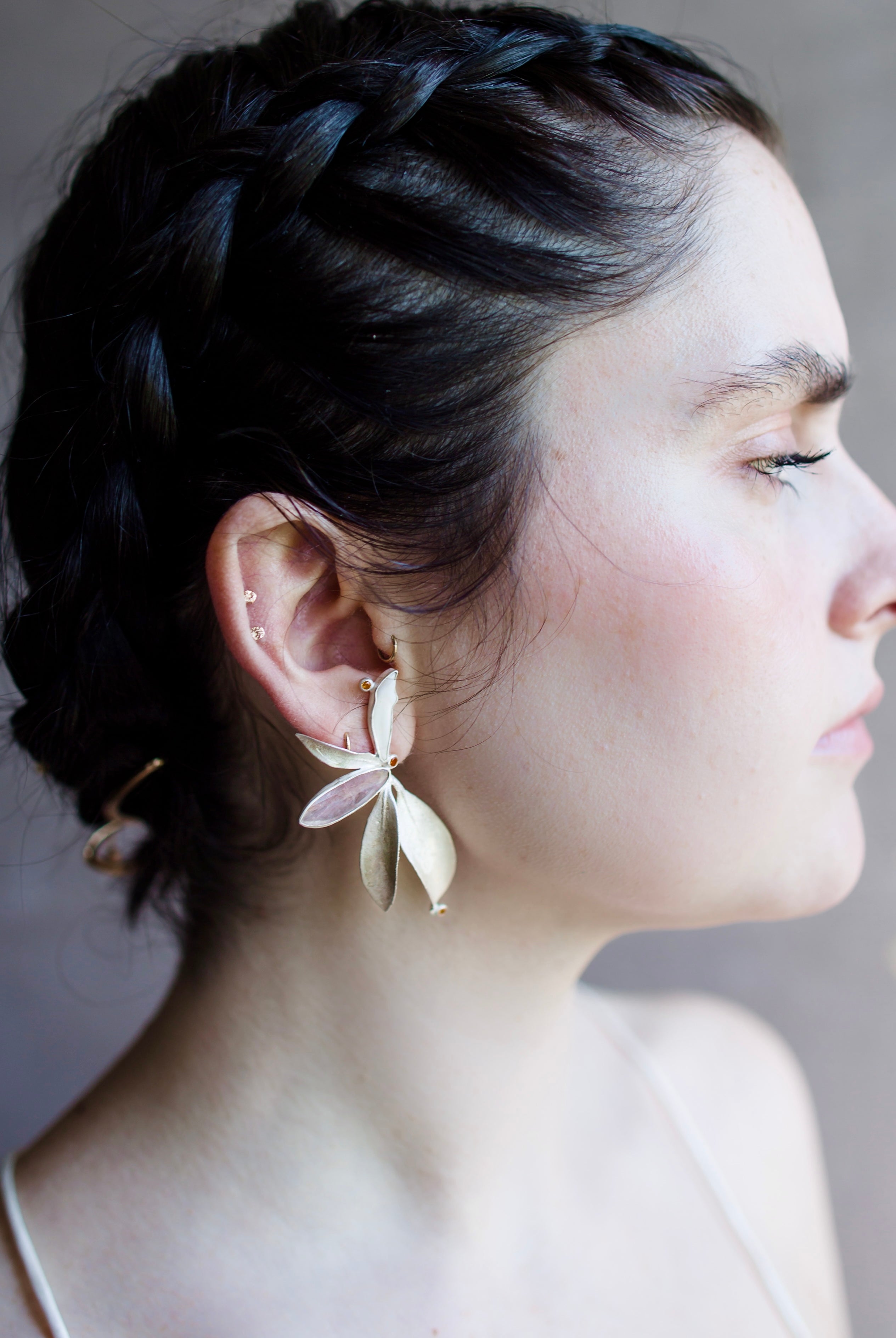 Image featuring a woman wearing North Carolina artist and jeweler Anna Johnson Kalmia Earrings with Teeth, cherry moonstone, topaz, depletion gilded silver, mountain laurel