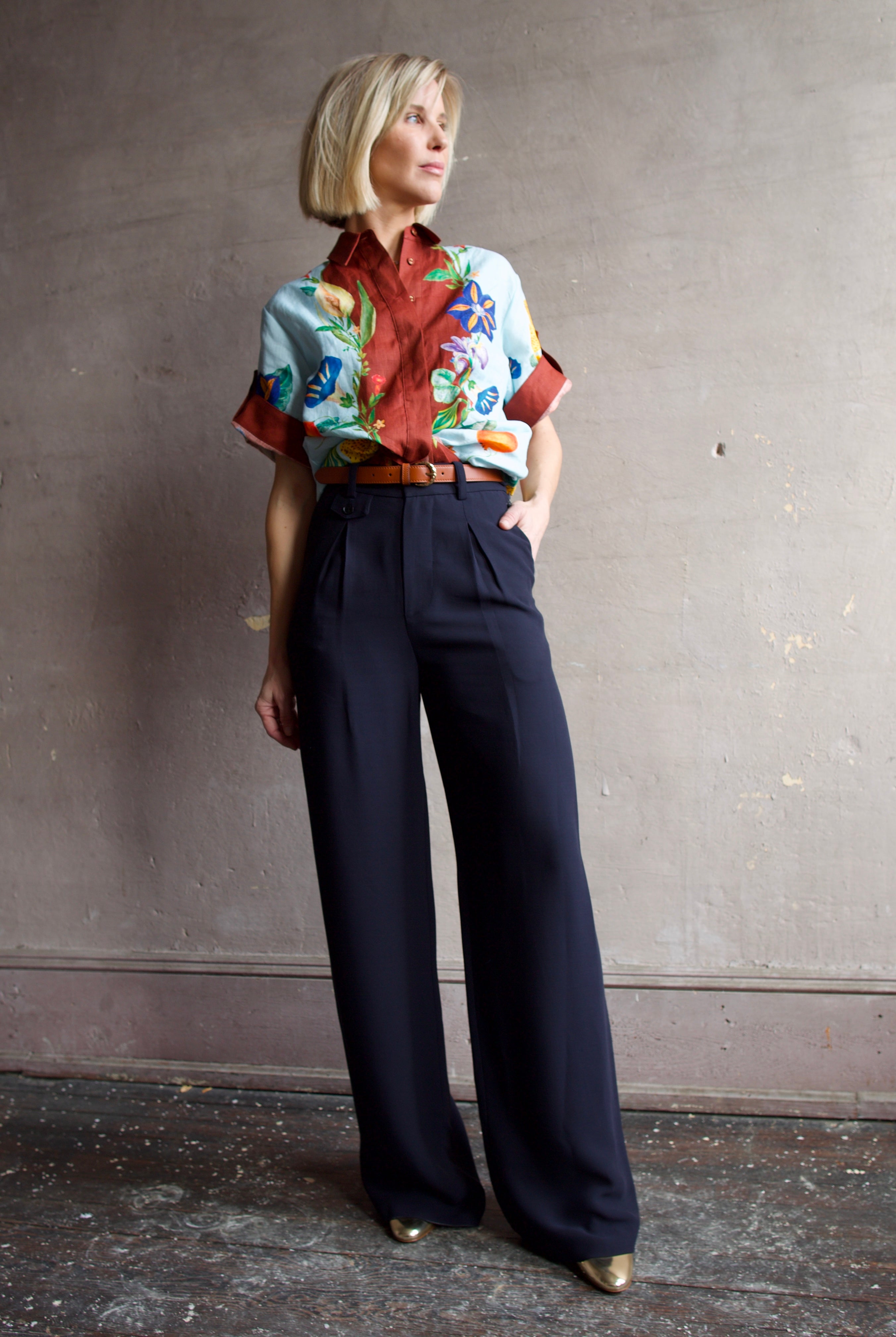 Image of a woman wearing the Alemais Dahlia Top and Apiece Apart Cara wide leg pants in navy blue with the Ulla Johnson Gia belt and Elise shoes.