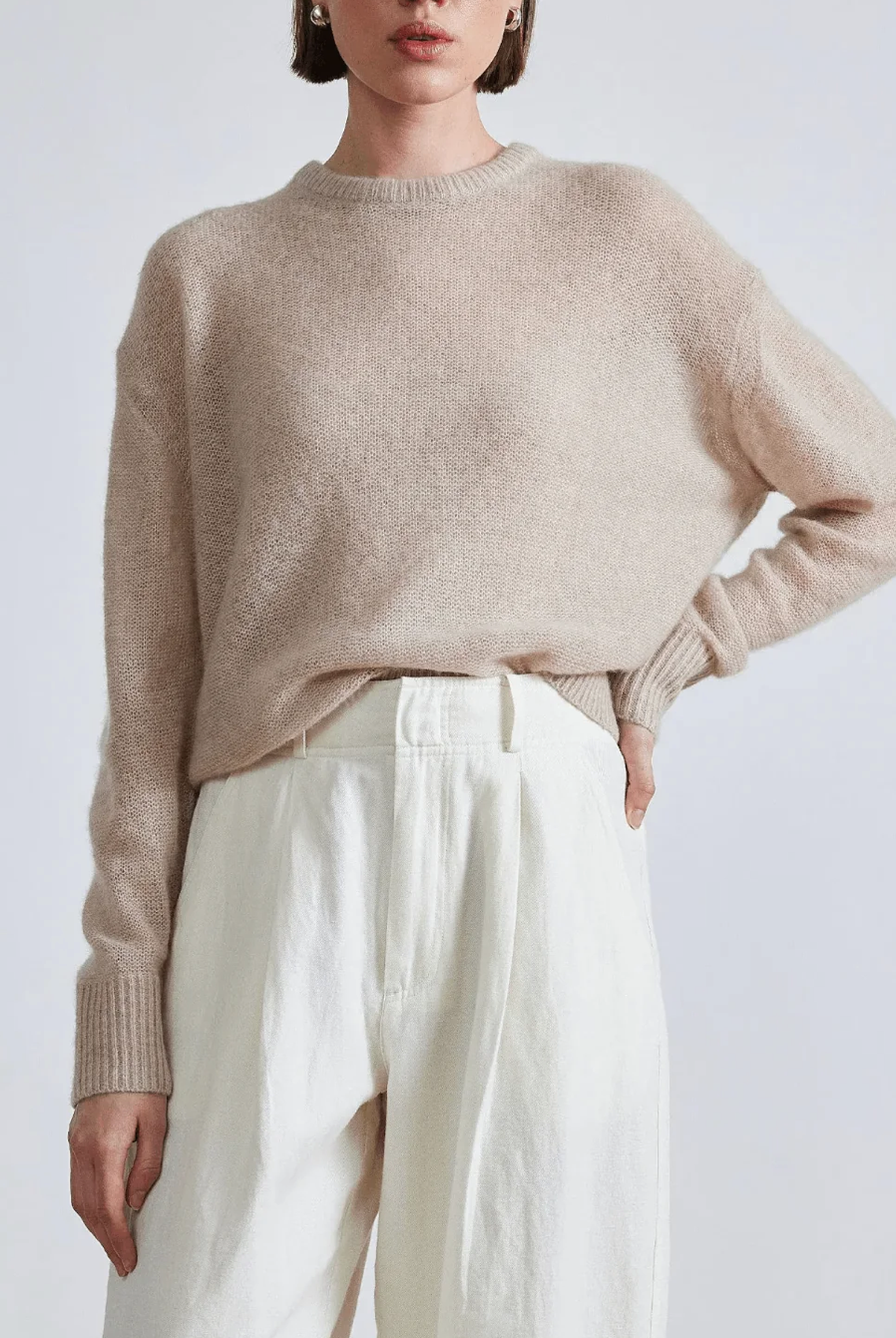 Model wearing Apiece Apart cashmere silk beige tissue weight sweater and white trousers