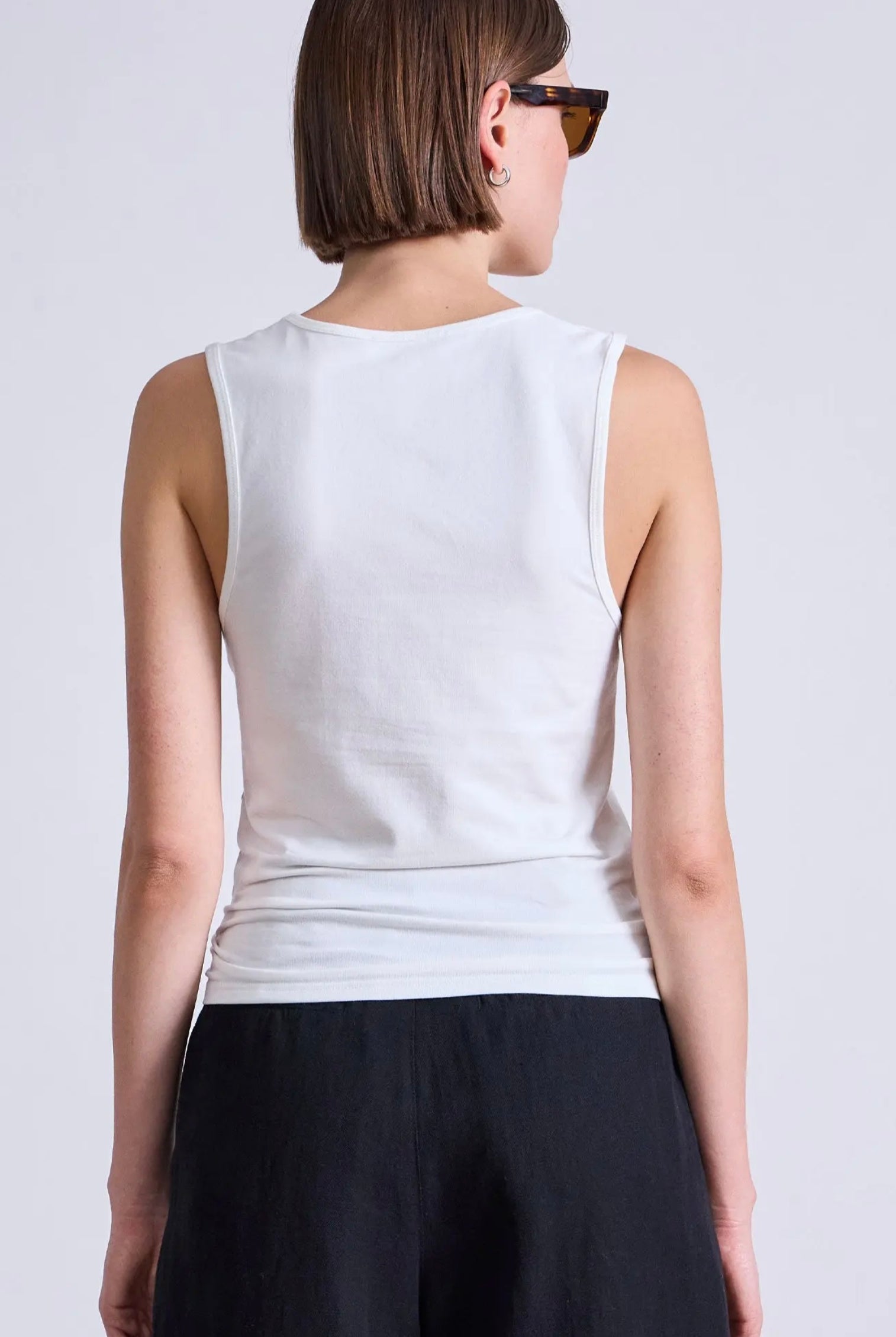 Model wearing a white cotton tank top with bra friendly back from Apiece Apart