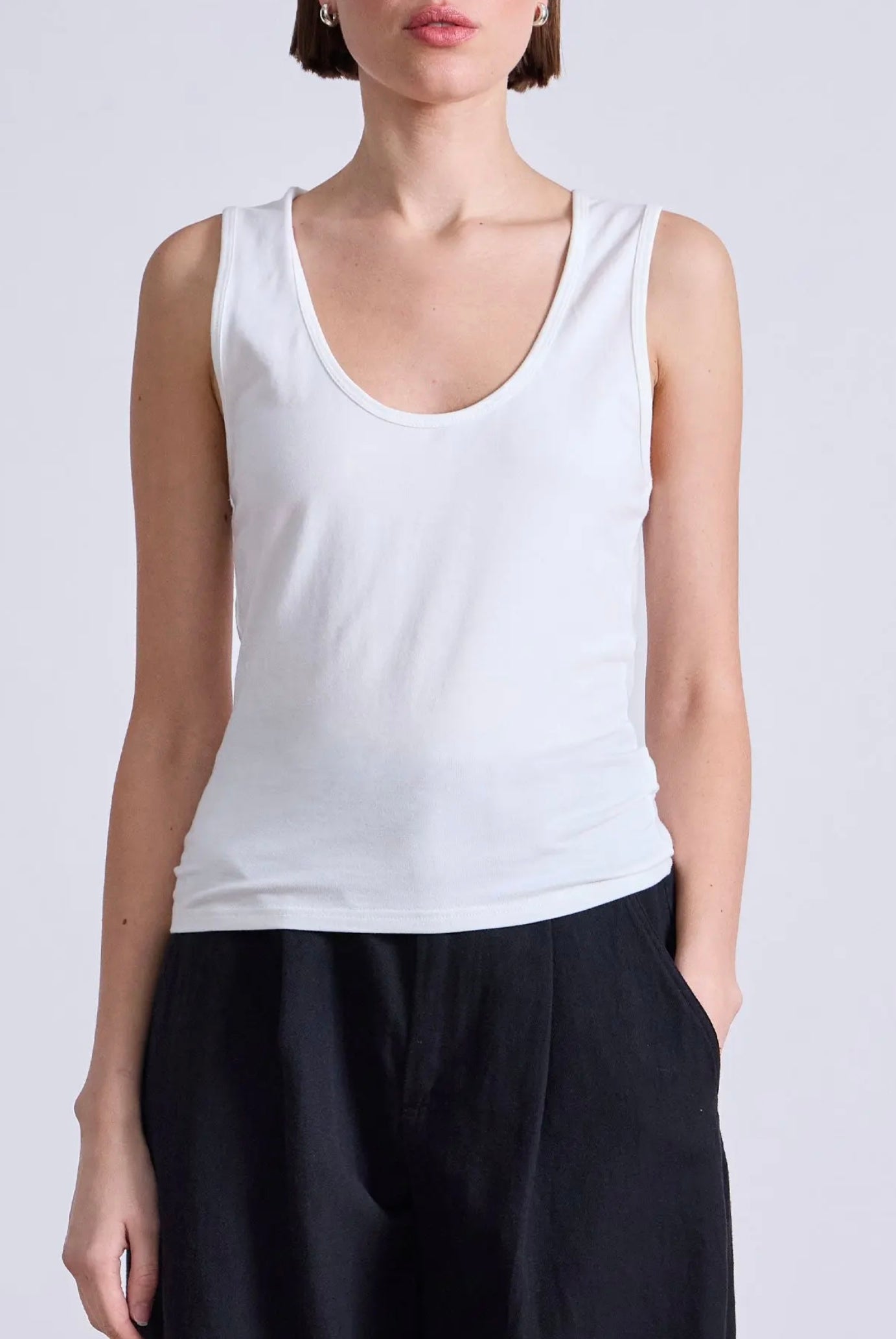 Model wearing a white cotton tank top with scoop neck and bra friendly shoulder straps from Apiece Apart