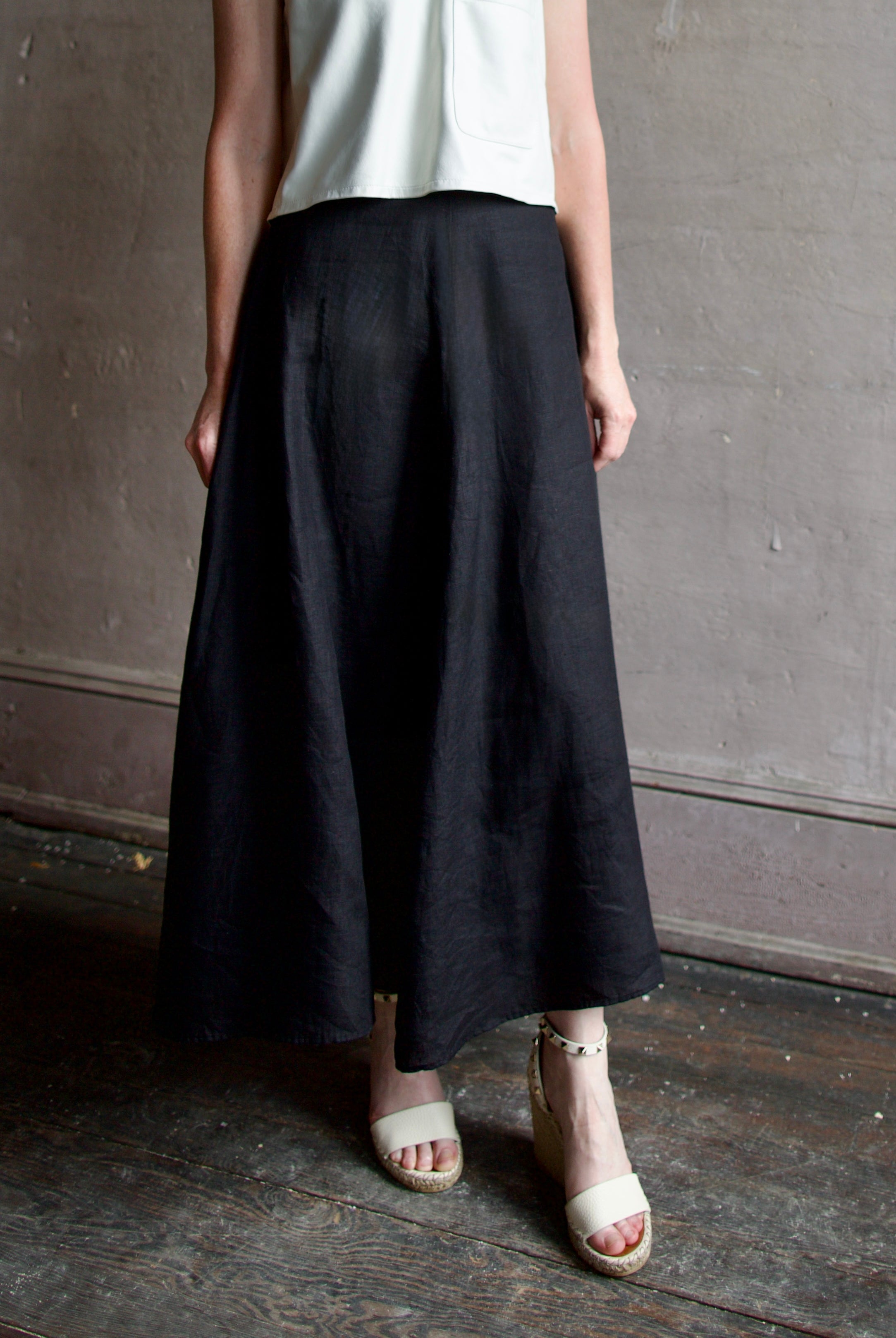 Model wearing contemporary designer Apiece Apart Primavera Drape black linen maxi A-line Skirt with quality tailoring and classic draping
