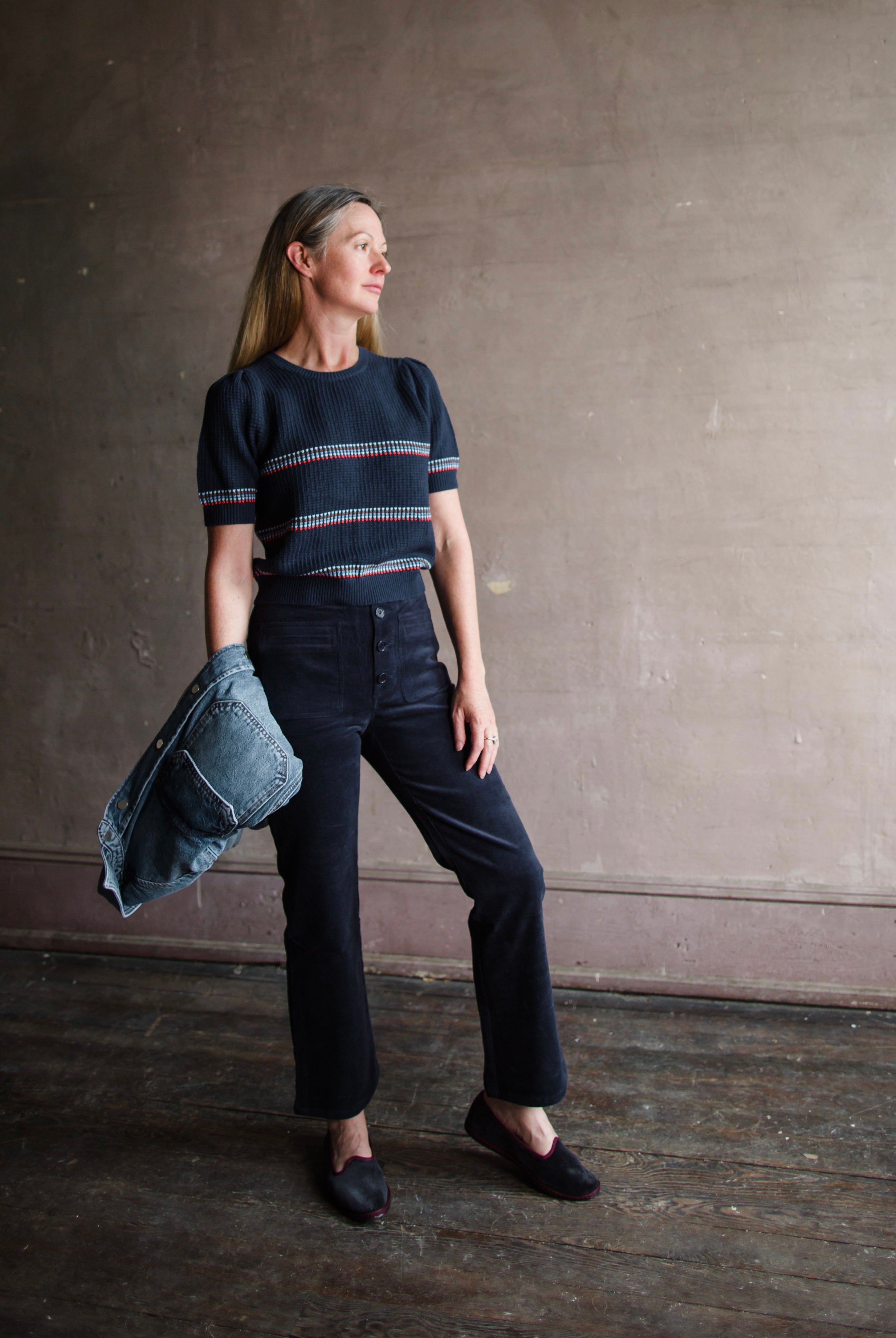 Image featuring a woman wearing the slim Marston corduroy pants by Apiece Apart with a high rise, button front, front patch pockets and a cropped, slightly flared leg in navy blue.