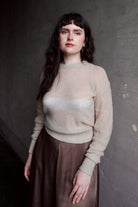 Model wearing Apiece Apart cashmere silk beige tissue weight sweater and brown skirt