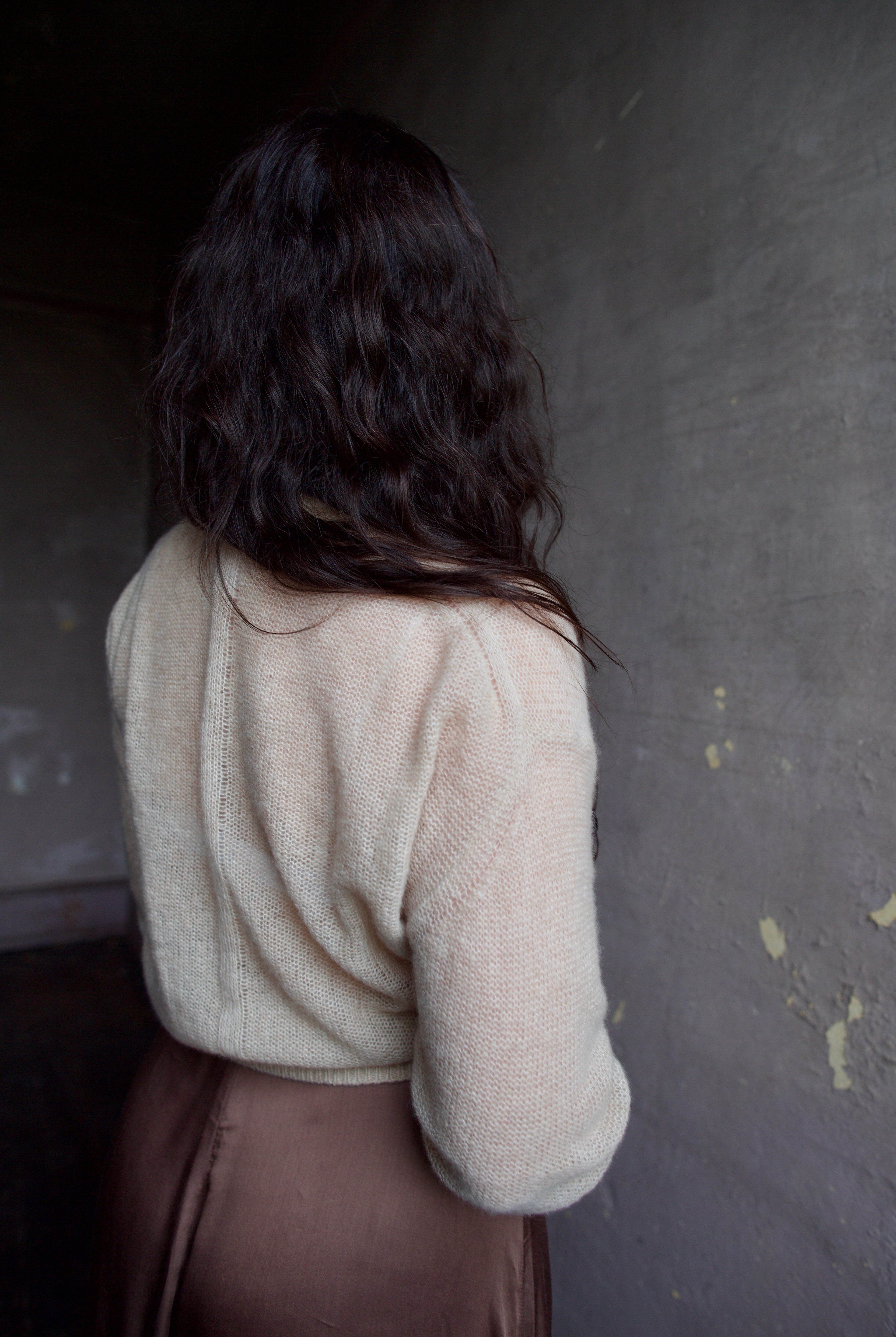 Model wearing Apiece Apart cashmere silk beige tissue weight sweater and brown skirt
