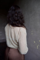 Model wearing Apiece Apart cashmere silk beige tissue weight sweater and brown skirt