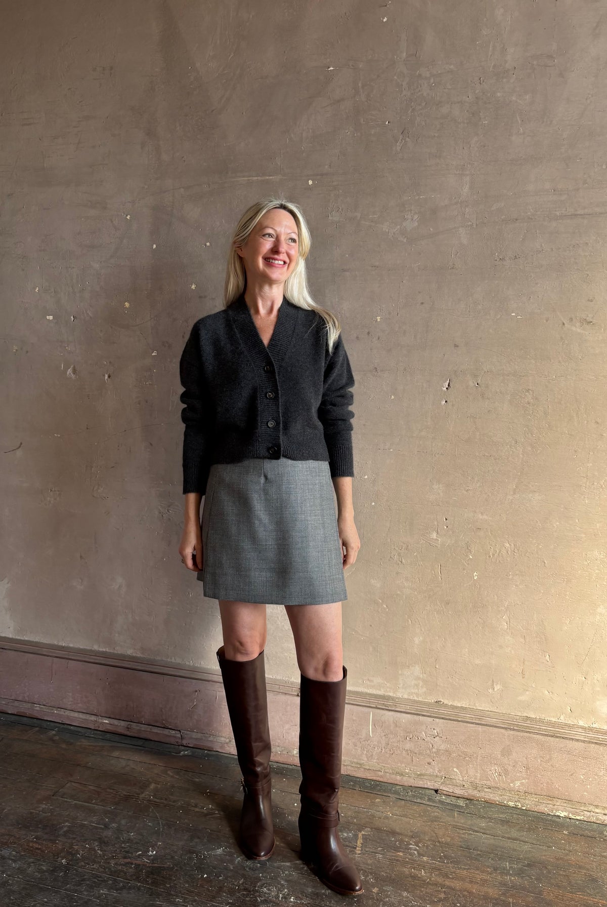 Mature woman wearing Apiece Apart's Marta virgin wool Mini Skirt in Heathered Grey sleek tailored silhouette styled with high boots for Fall