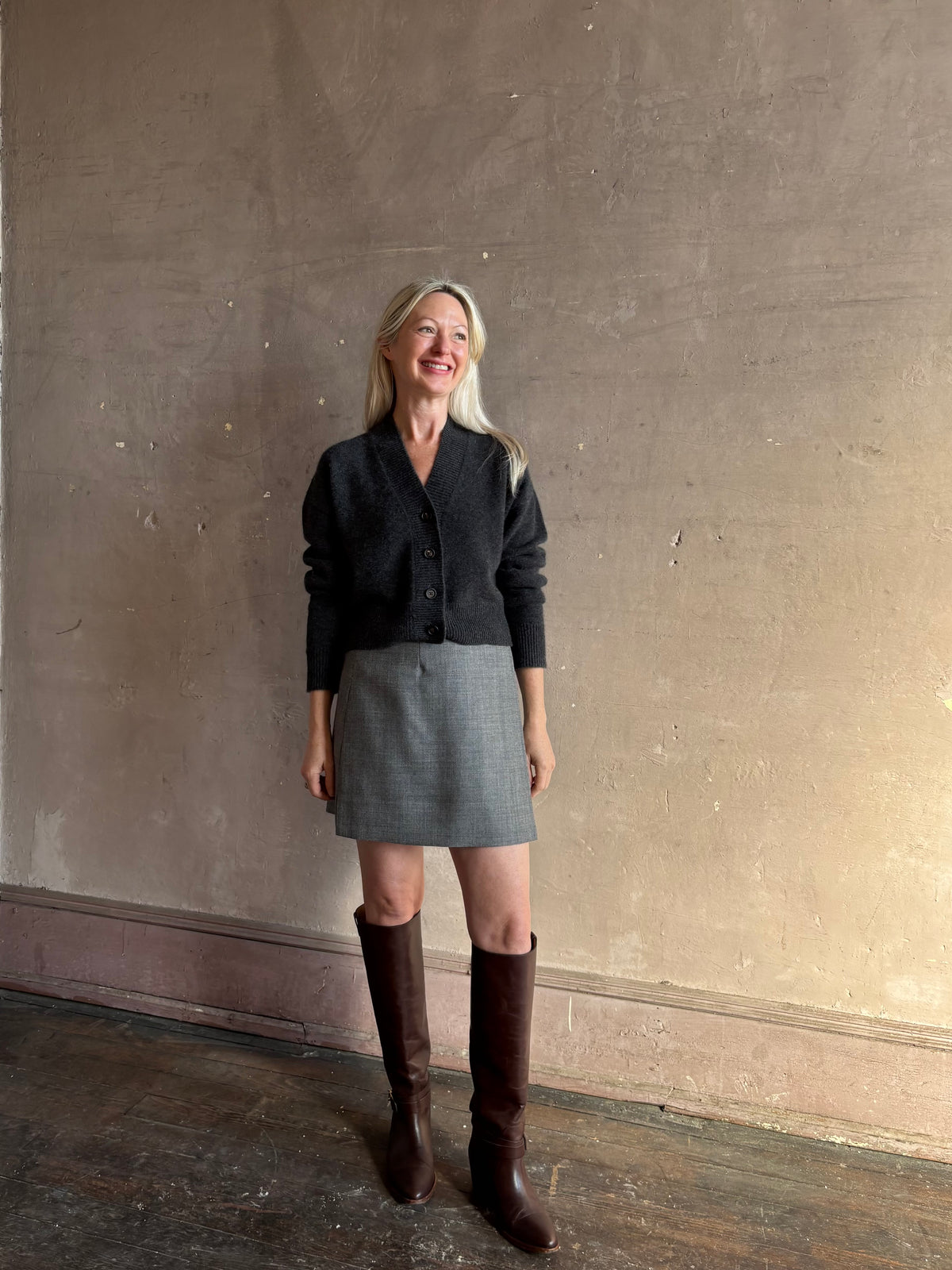 Mature woman wearing Apiece Apart's Marta virgin wool Mini Skirt in Heathered Grey sleek tailored silhouette styled with high boots for Fall