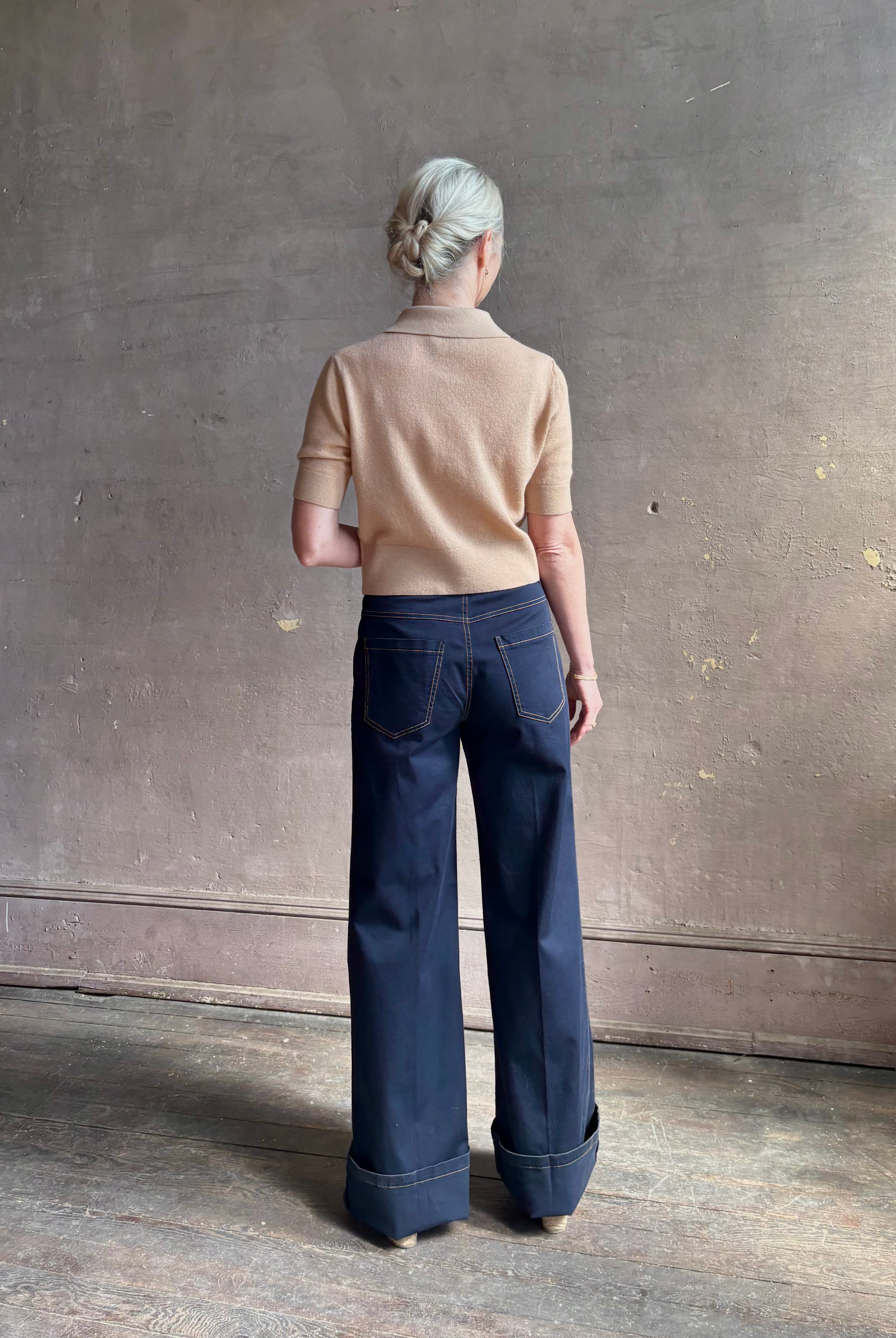 Mature woman wearing the European tailored Jane mid-rise Pant from Callas rendered in a timeless navy and crafted from a stretchy cotton blend featuring yellow stitching, a clean flat front and flattering back pockets