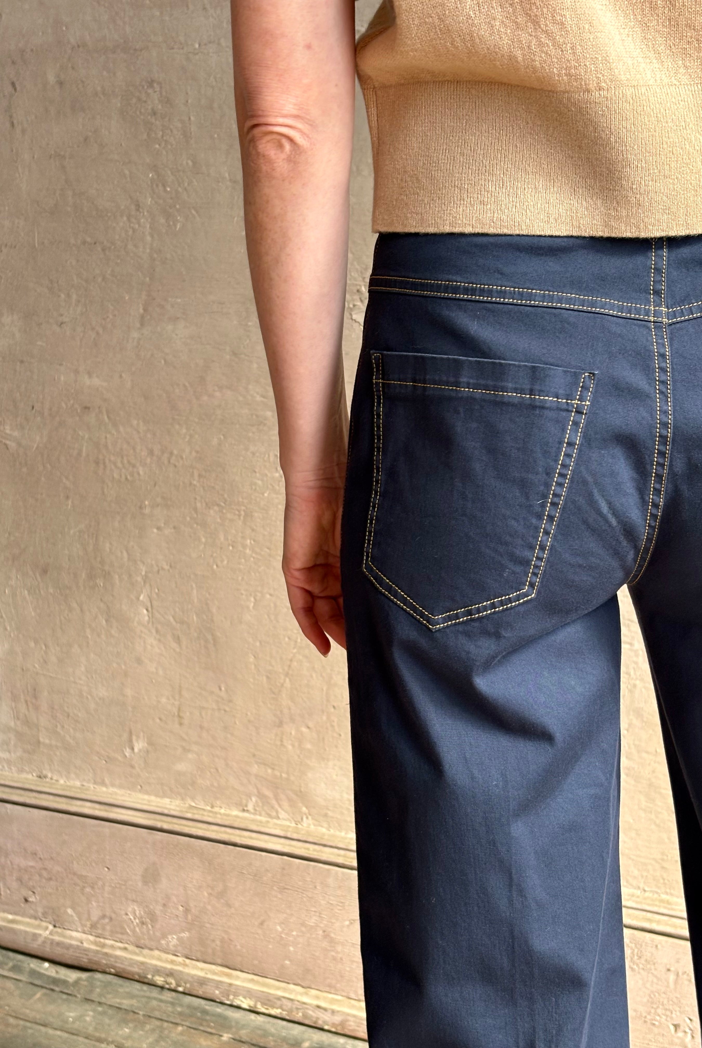 Mature woman wearing the European tailored Jane mid-rise Pant from Callas rendered in a timeless navy and crafted from a stretchy cotton blend featuring yellow stitching, a clean flat front and flattering back pockets