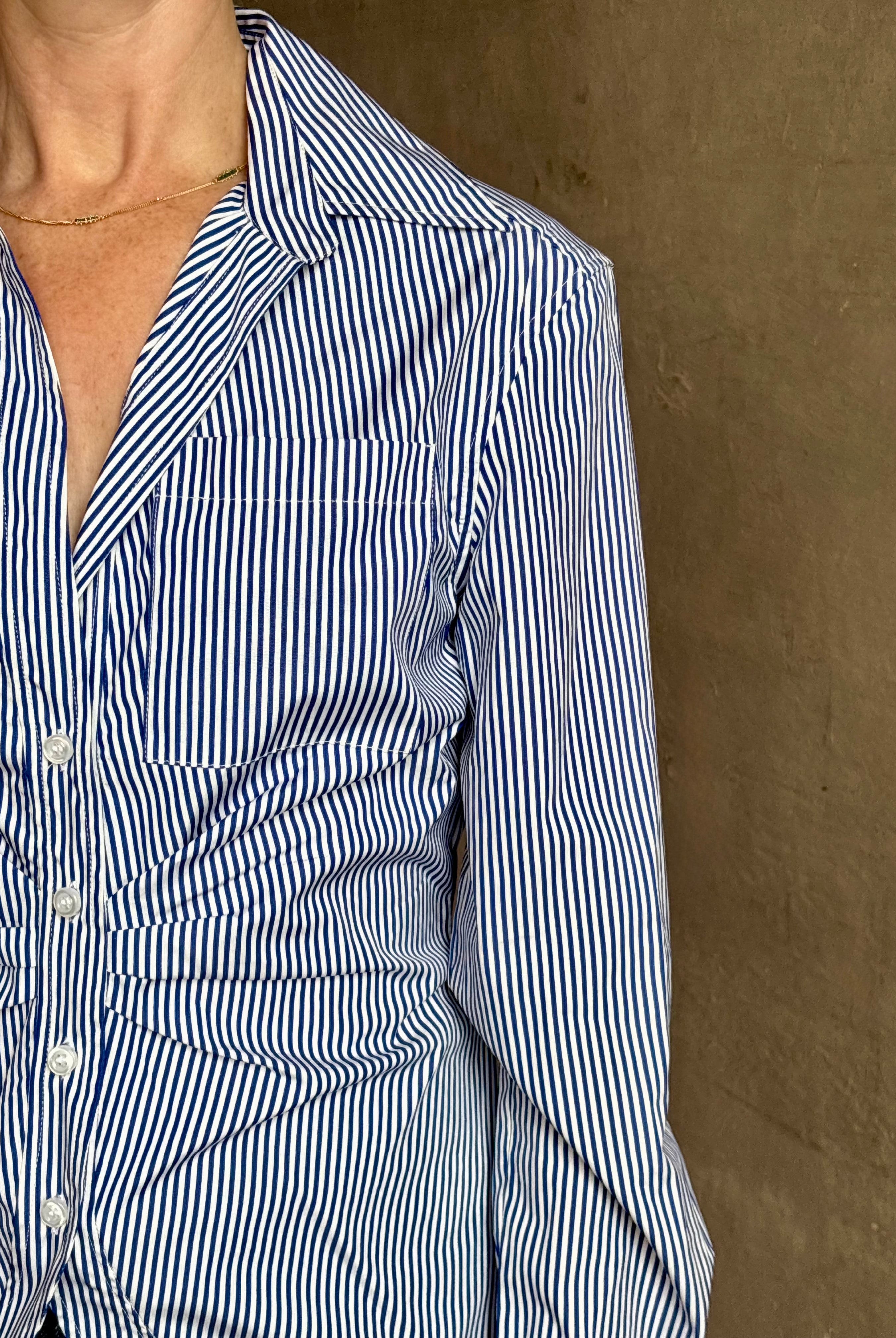 Mature woman wearing the European tailored Sierra Shirt from Callas rendered in a crisp navy and white stripe and crafted from cotton poplin featuring a flattering ruched front , long sleeves, v-neck and rounded bottom detail