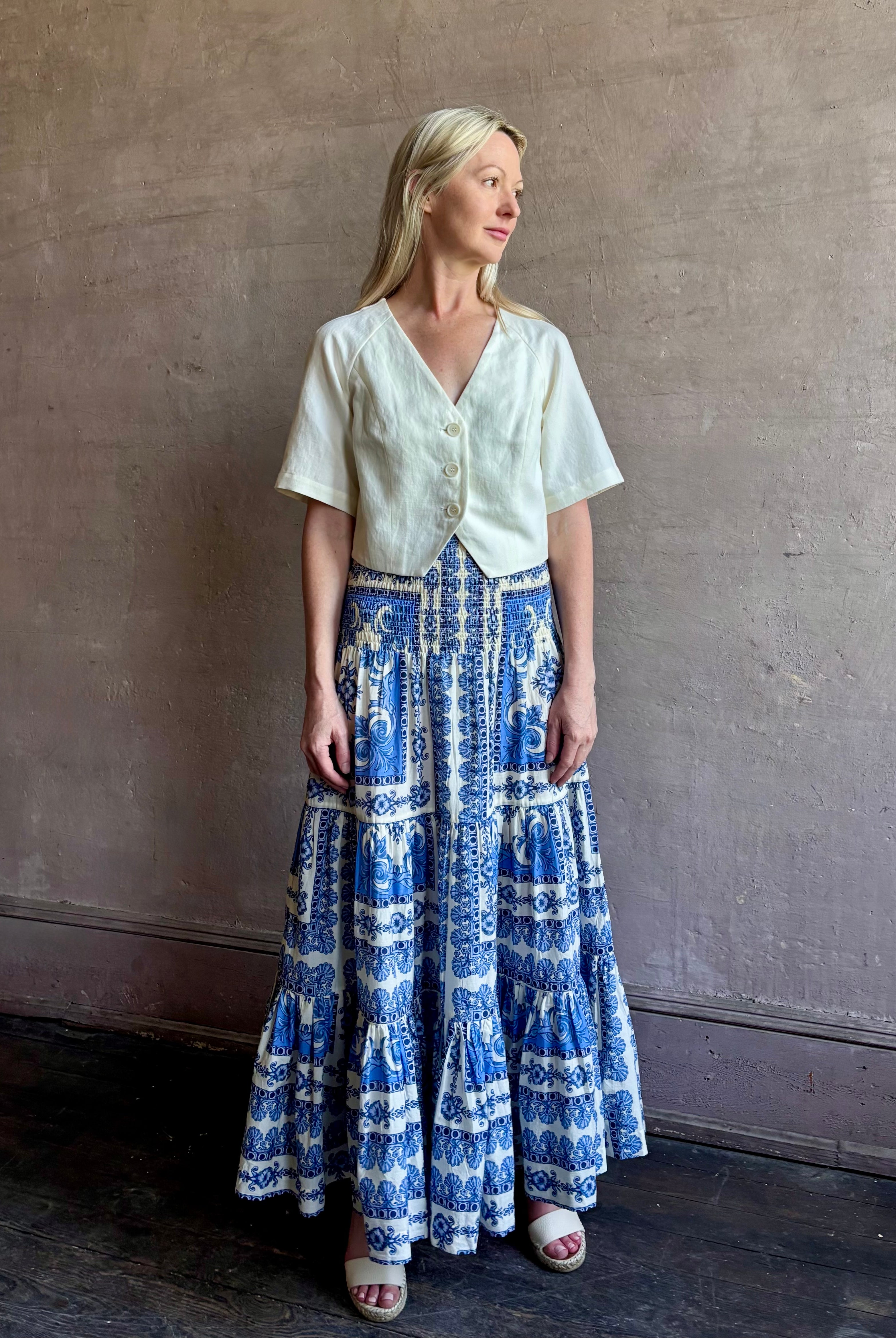 Mature woman wearing Emilia Skirt from Cara Cara rendered in the Hudson Scarf Sky blue and white print crafted from 100% cotton with shirred drop waist and ruffled tiered full skirt
