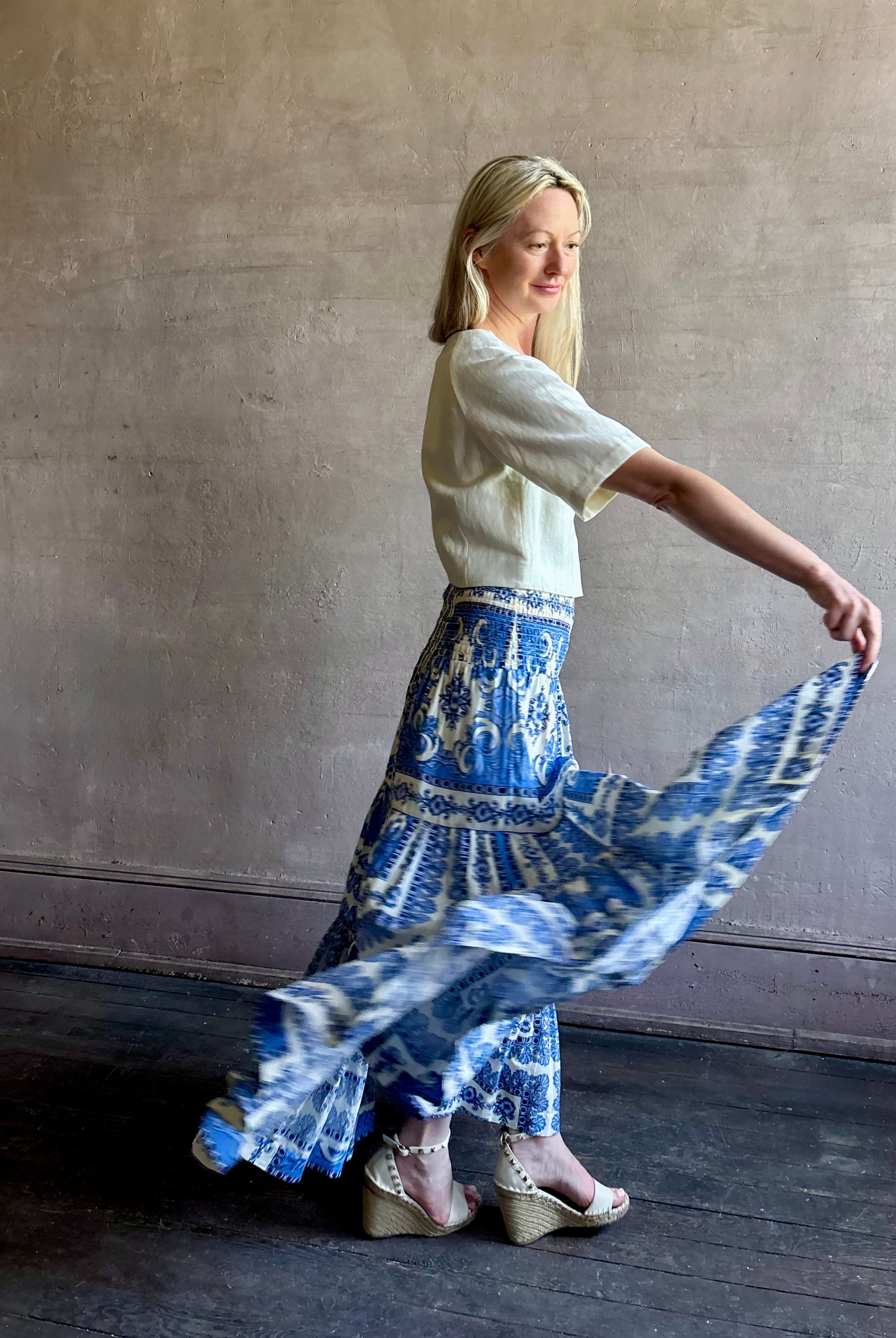 Mature woman wearing Emilia Skirt from Cara Cara rendered in the Hudson Scarf Sky blue and white print crafted from 100% cotton with shirred drop waist and ruffled tiered full skirt
