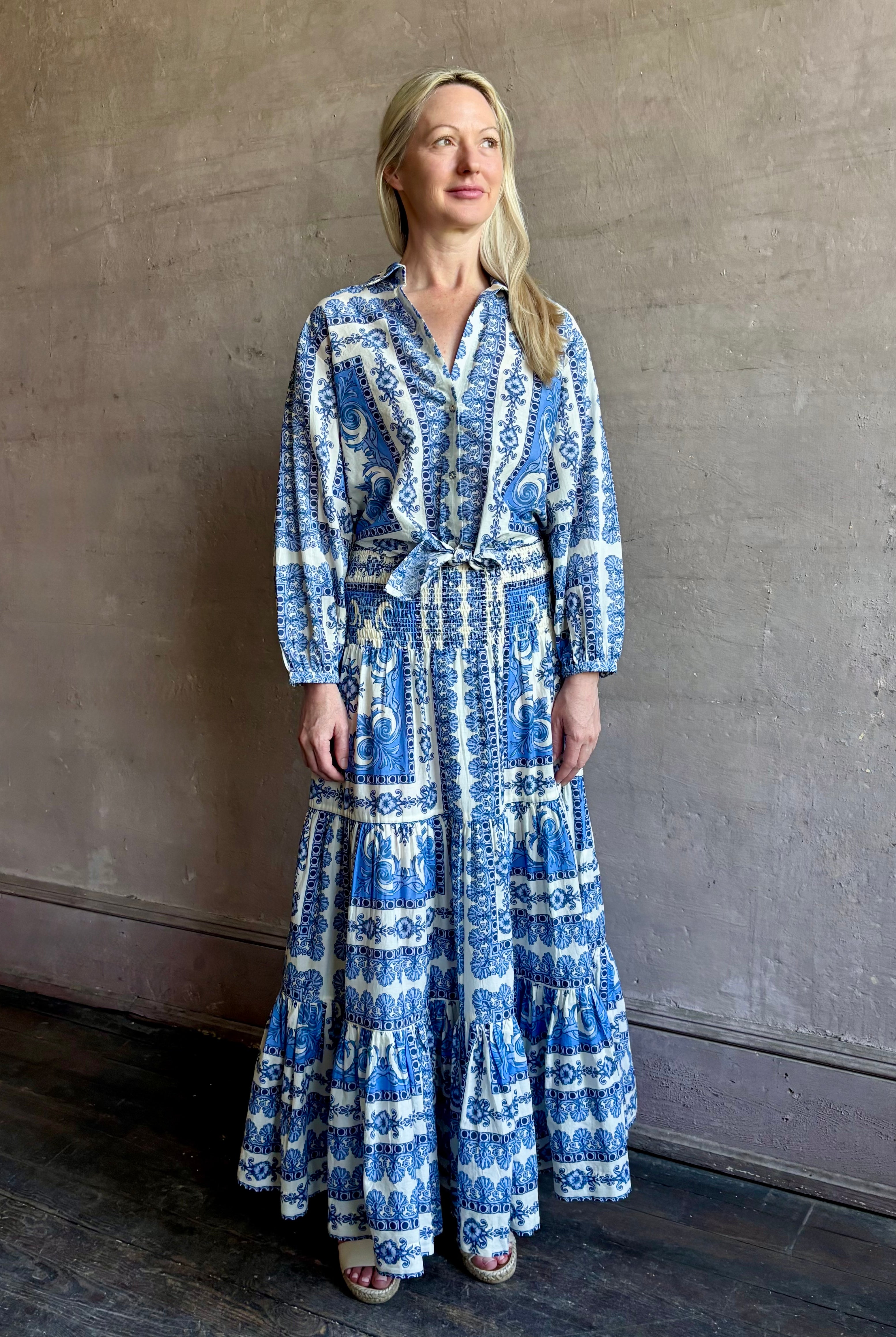 Mature woman wearing Emilia Skirt from Cara Cara rendered in the Hudson Scarf Sky blue and white print crafted from 100% cotton with shirred drop waist and ruffled tiered full skirt